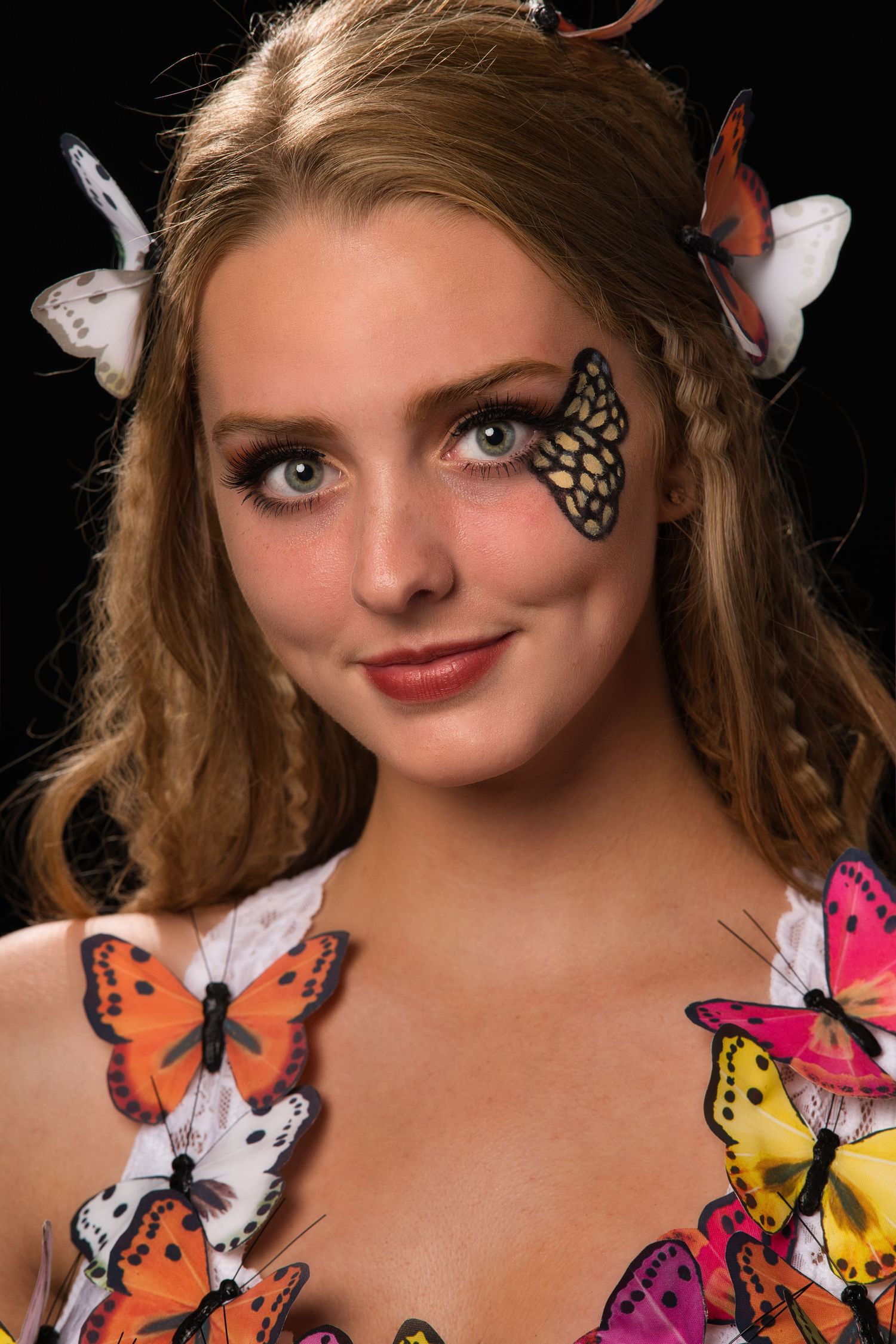 Young woman with colorful butterflies on face and dress posing.