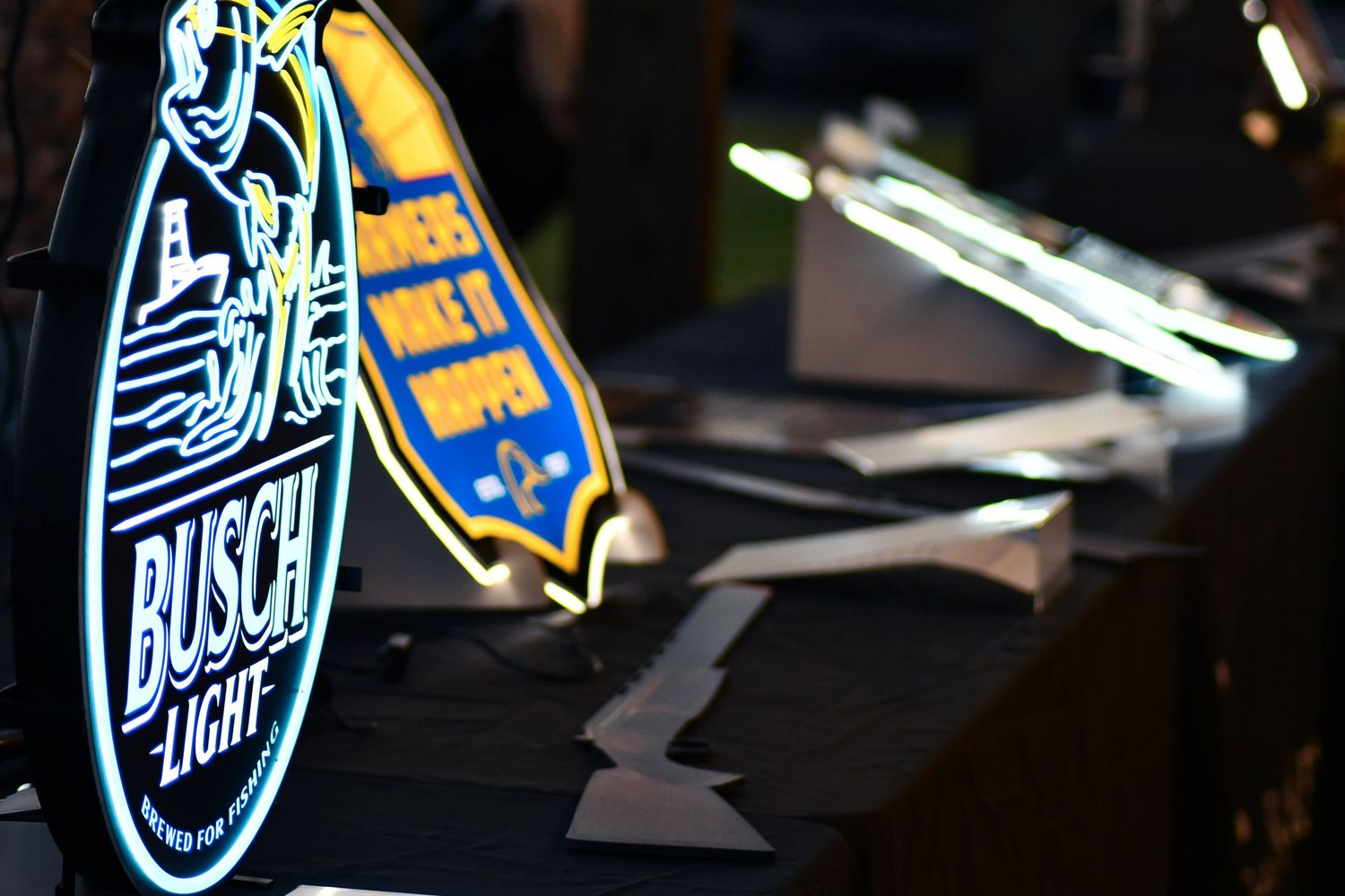 Busch Light neon sign glowing on a table at an indoor event.