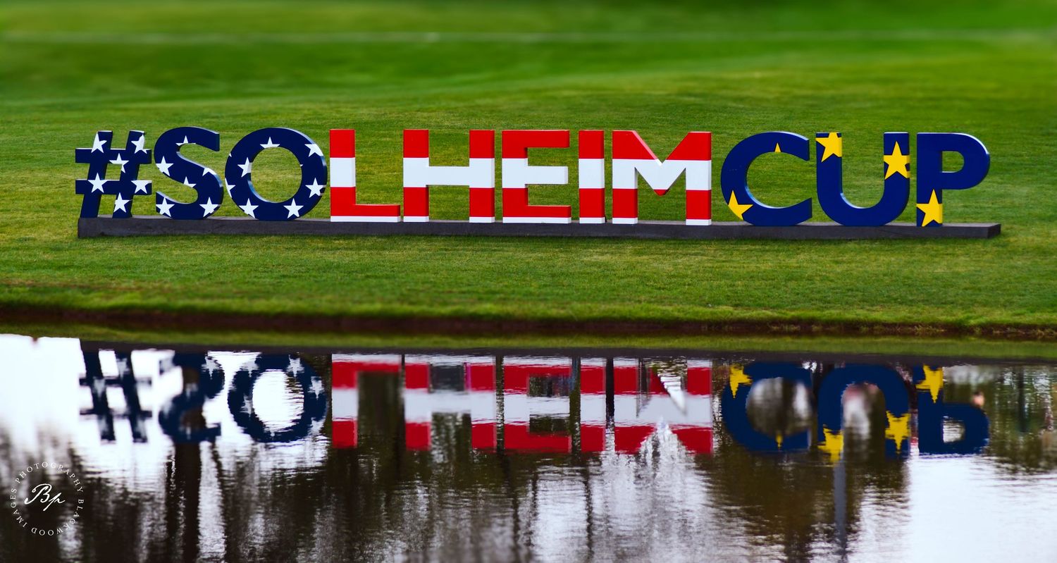 Solheim Cup logo sign reflected in water at golf tournament venue.
