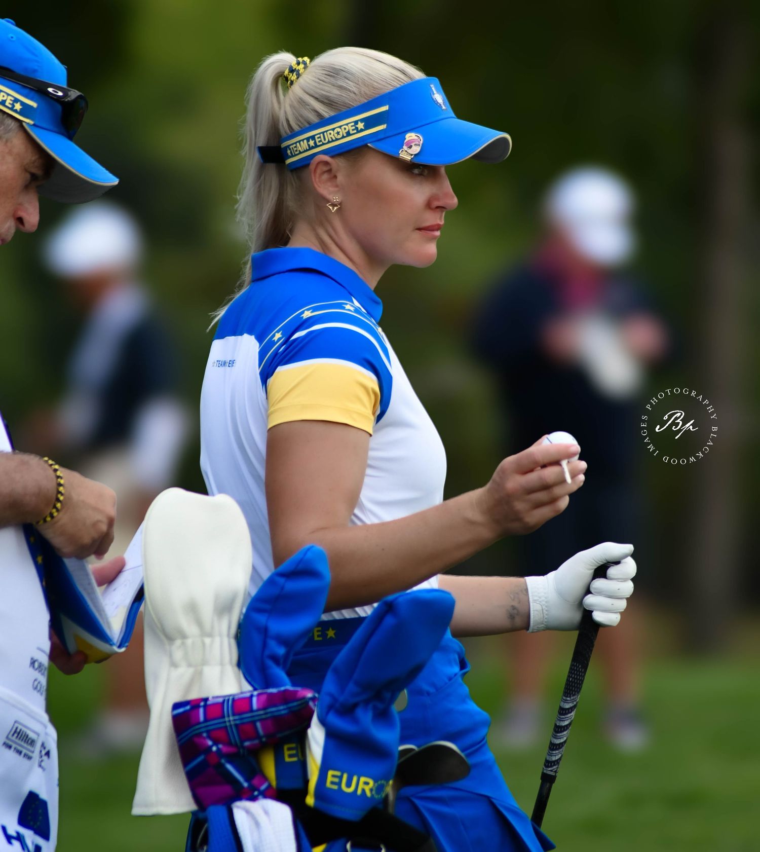 Female European team golfer in blue and yellow uniform walking the course during competition.