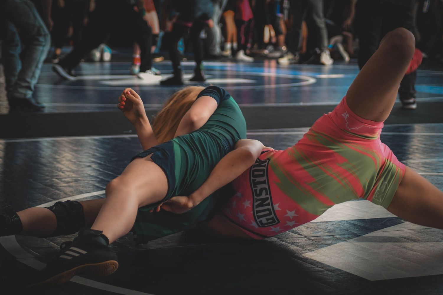 Two youth wrestlers competing on mat during indoor wrestling tournament match.
