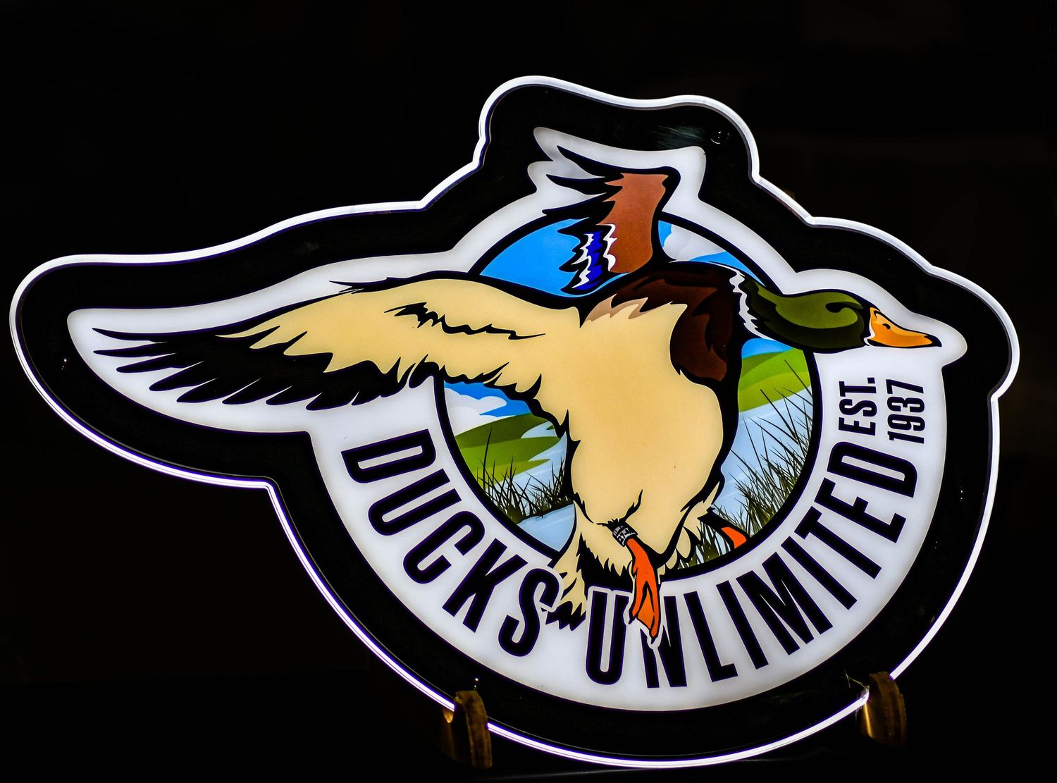 Ducks Unlimited Est. 1937 illuminated neon sign featuring a colorful mallard duck in flight.