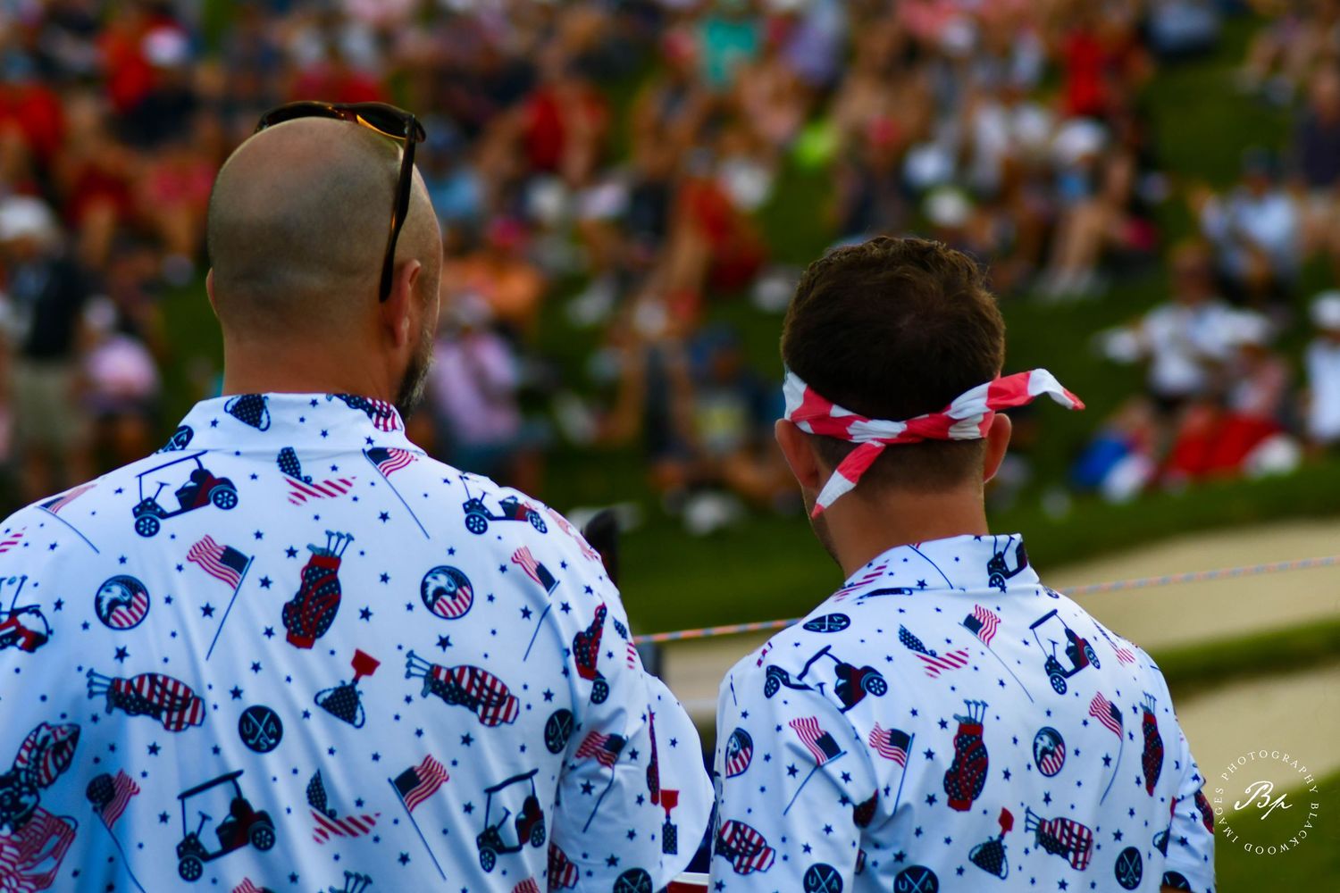 Two men wearing matching patriotic American-themed button-up shirts at an outdoor event.