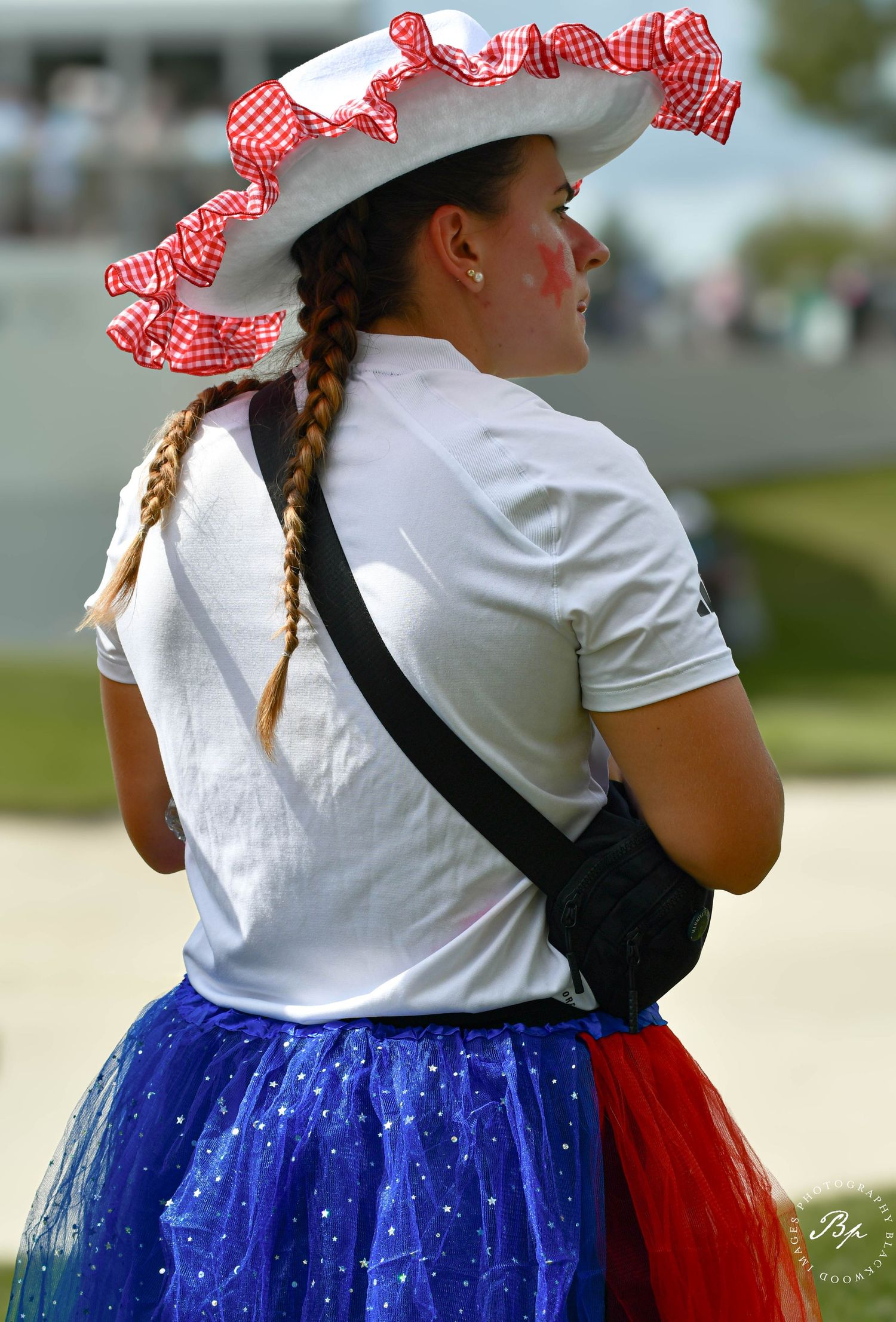 Young woman in red white and blue tutu skirt and ruffled hat at patriotic event.