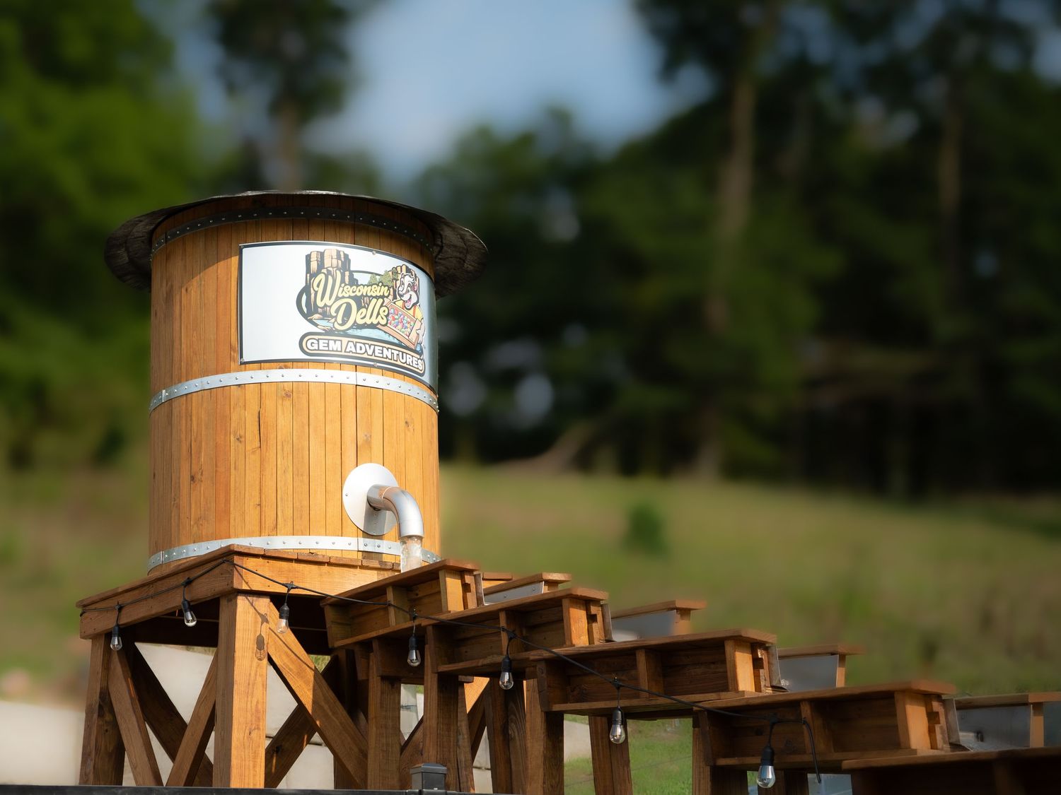 Rustic wooden water tower with branded signage on a raised timber frame structure outdoors.