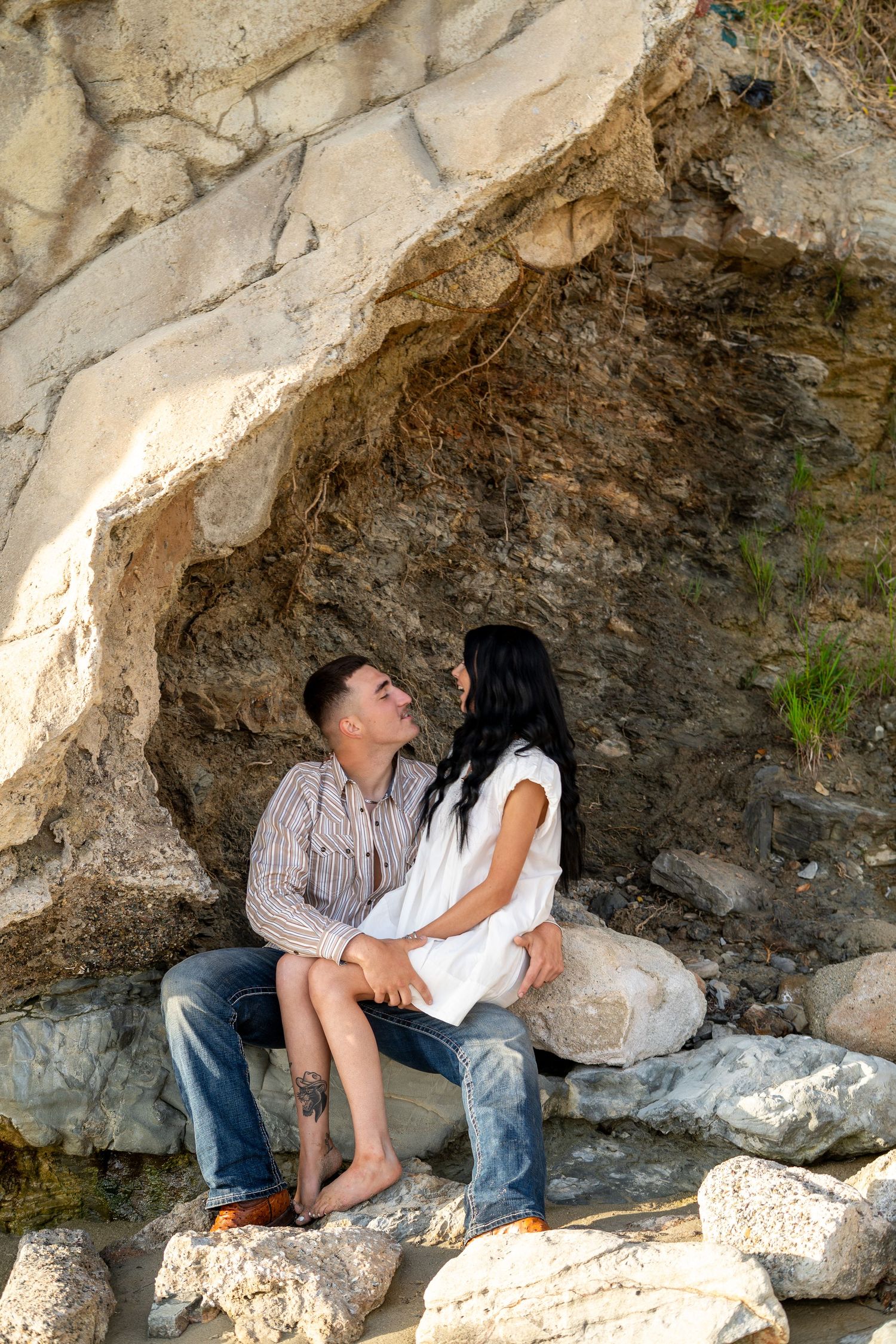 Romantic couple sharing an intimate moment sitting together in a natural rocky cave alcove.