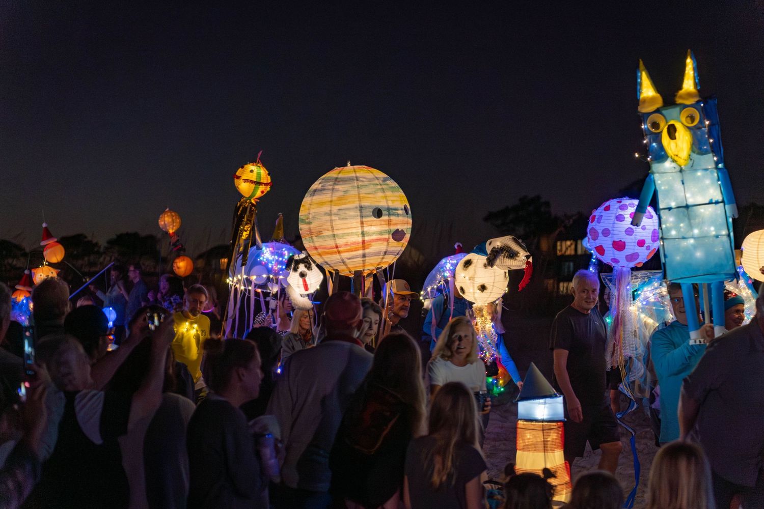 Crowds watch colorful character lanterns, glowing jellyfish, and whimsical sea creatures move through the beach at the Hilton Head Parade.