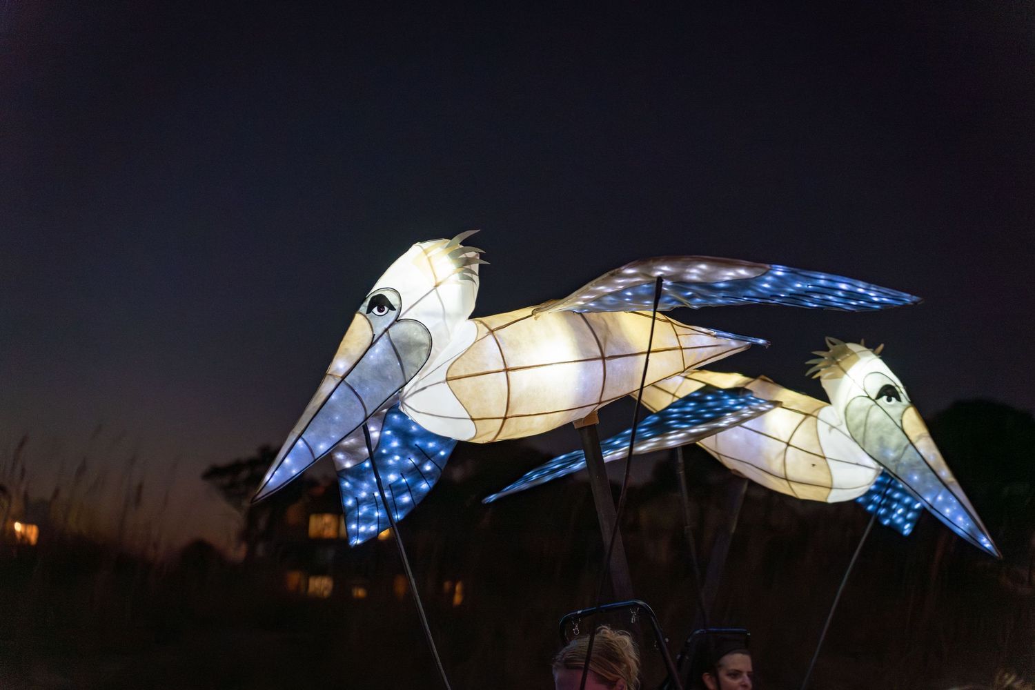 Large glowing sea turtle lantern carried by a performer as onlookers gather at the Hilton Head beach parade.