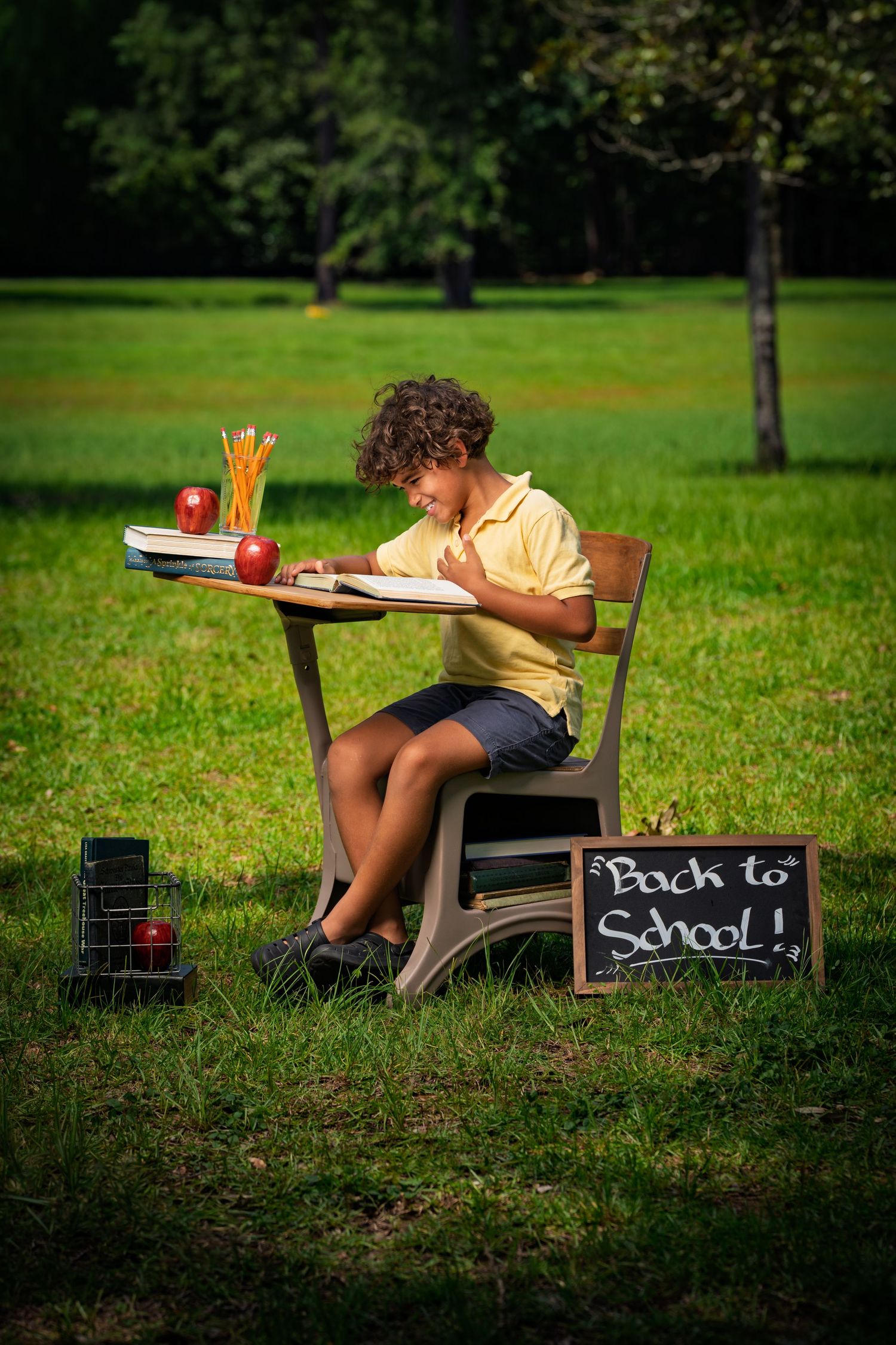 Boy reading at a school desk during a back-to-school photo session at Red Barn Park at New Riverside in Bluffton, SC.