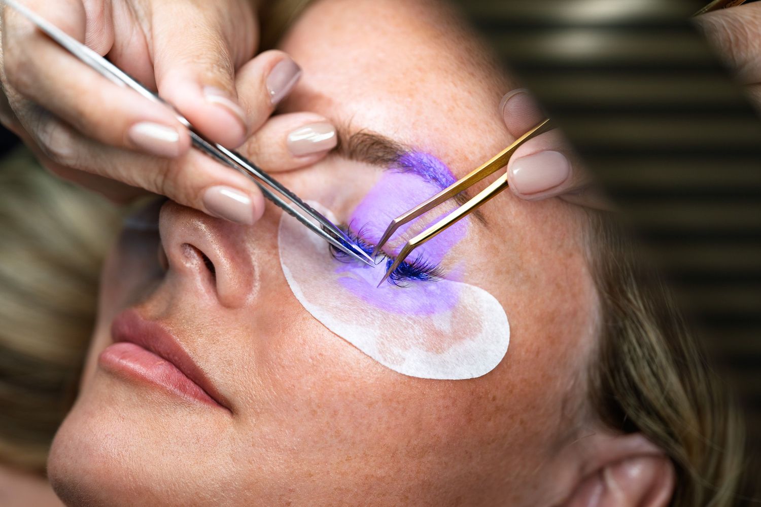 Detailed view of a lash artist applying eyelash extensions with
precision tweezers during a professional lash service in Bluffton,
SC.