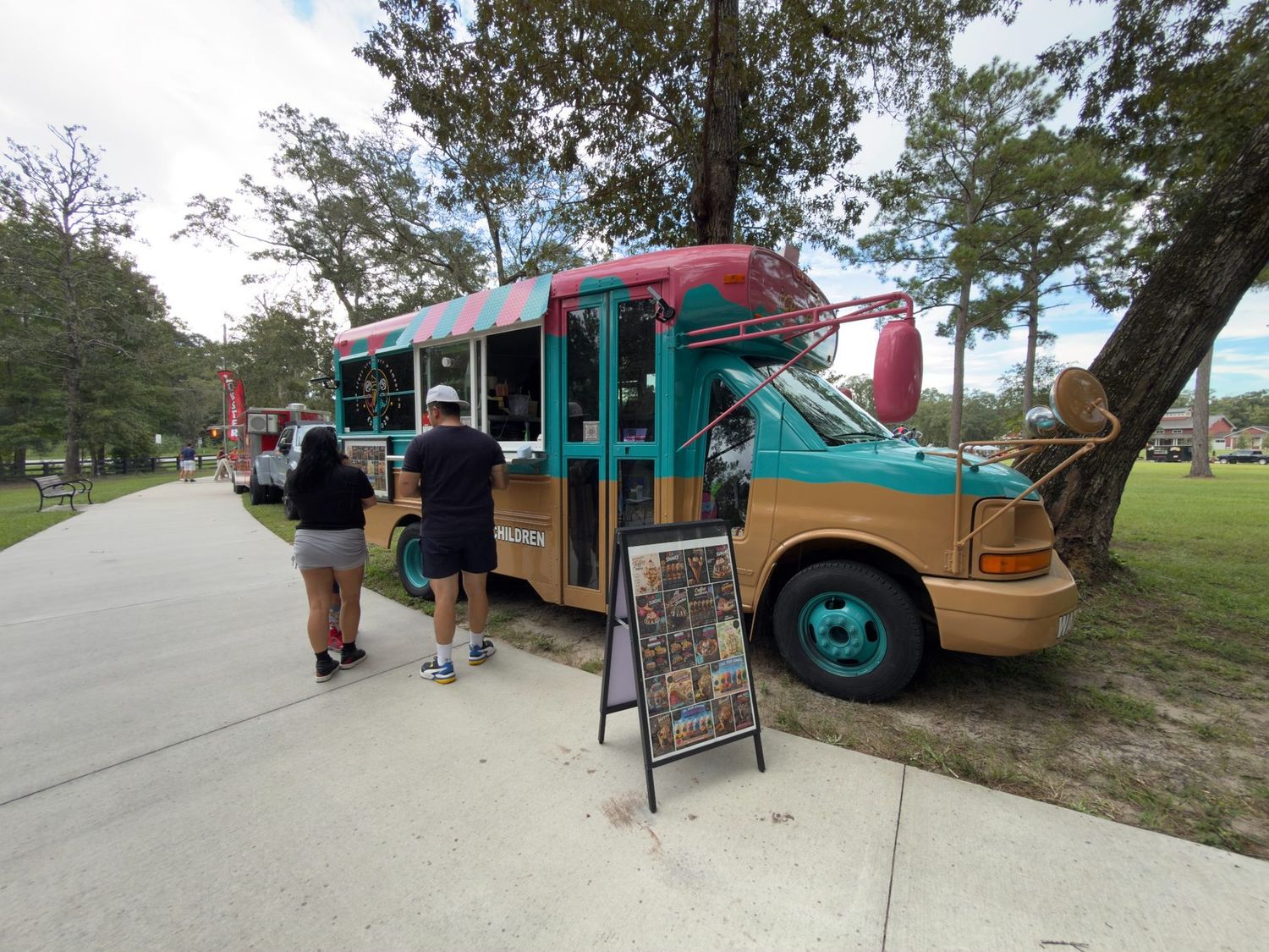 Colorful turquoise and pink dessert food truck with customers ordering during
Taste of Bluffton 2026 at New Riverside Barn Park in Bluffton,