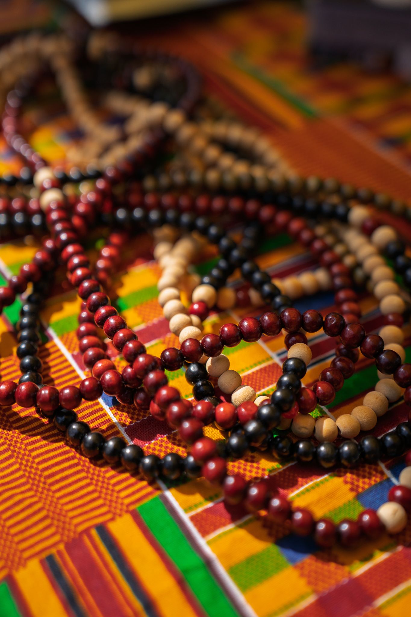 Handmade wooden bead bracelets displayed on colorful African-inspired fabric during the Bluffton Farm and Flea grand opening in Bluffton, So