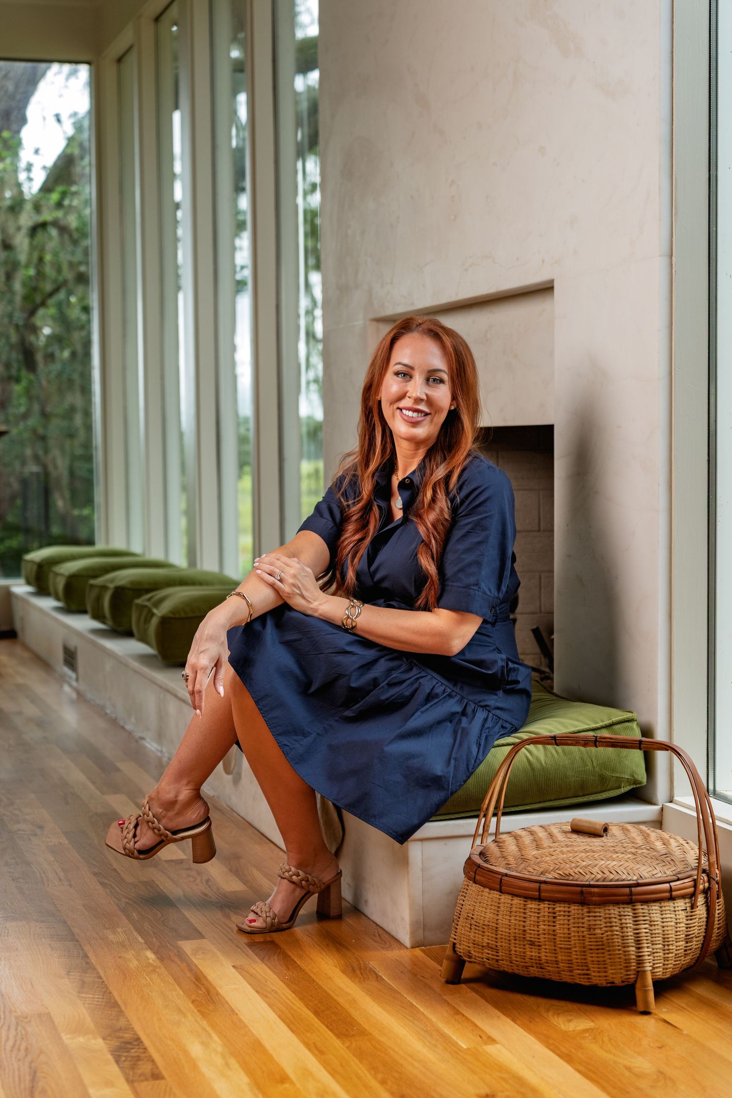 Female Realtor seated beside floor-to-ceiling windows during a professional personal branding session in a bright Lowcountry home, smiling