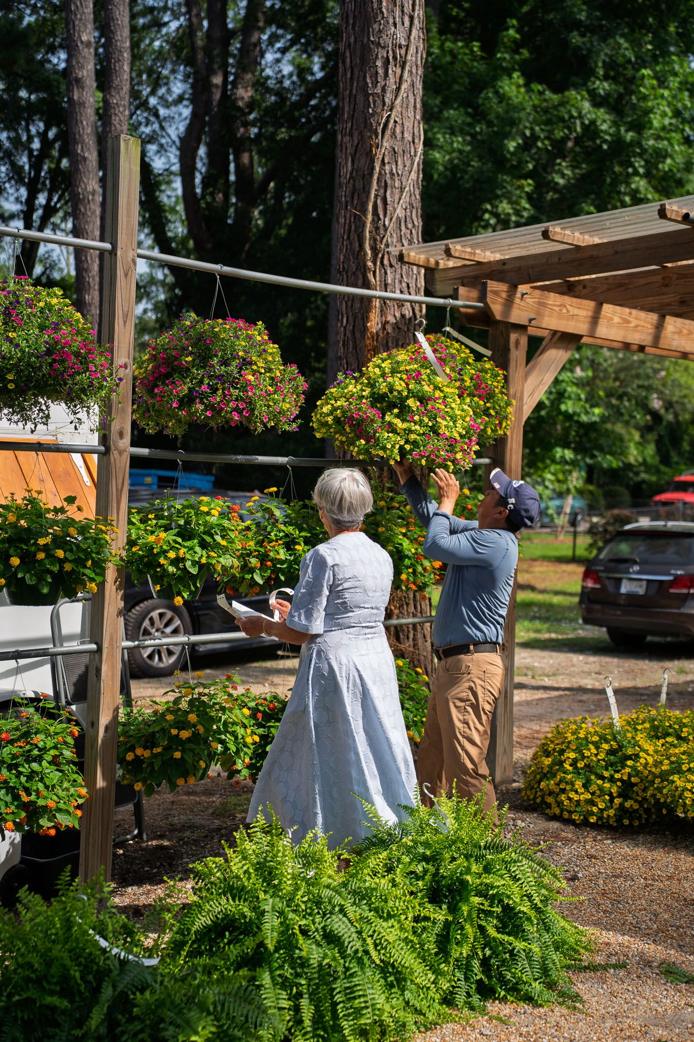 Visitors browse colorful hanging flower baskets during the opening weekend at Bluffton Farm and Flea in Bluffton, South Carolina.