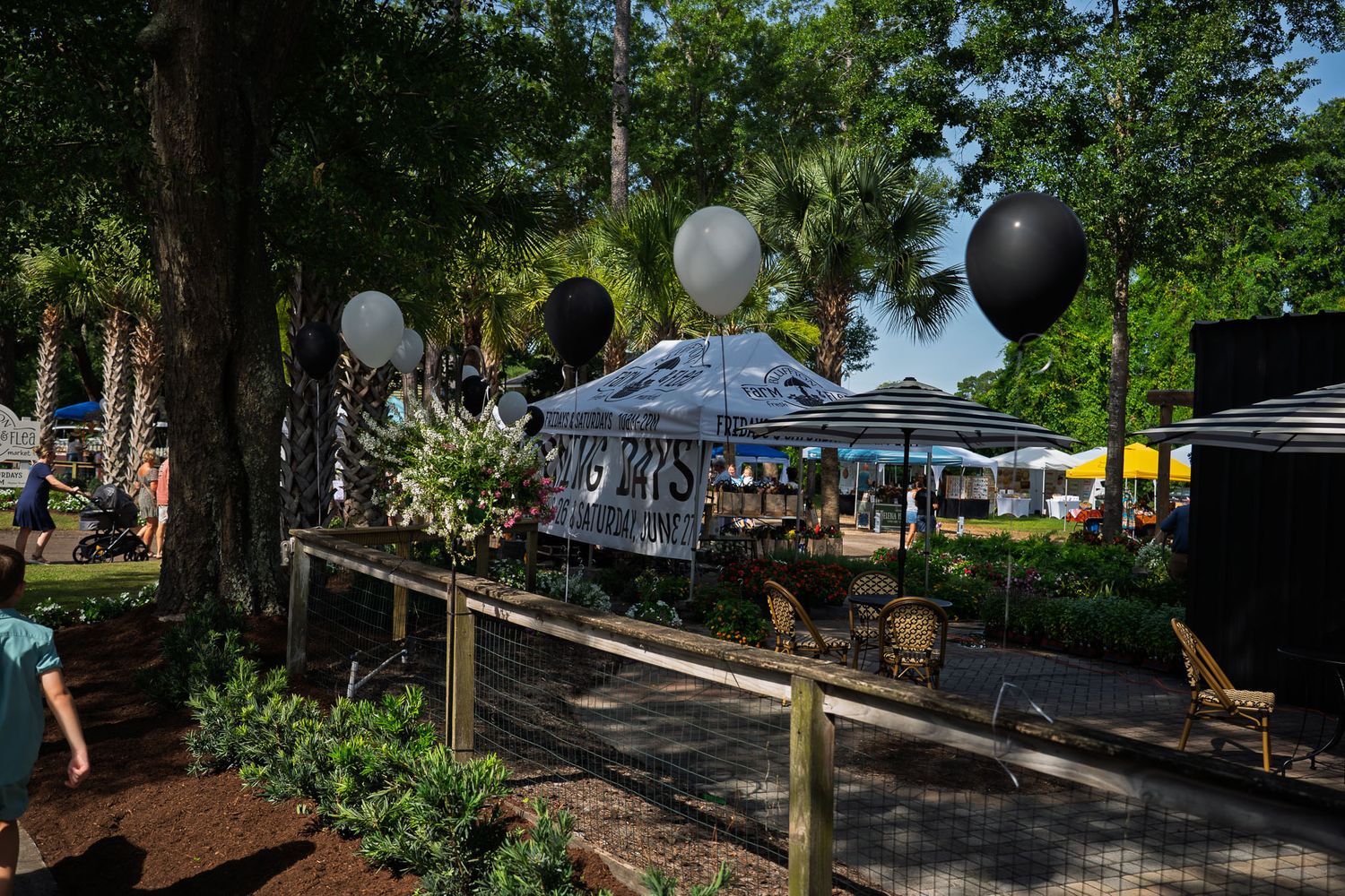A large crowd gathers near the Bluffton Farm and Flea entrance sign on opening day in Bluffton, South Carolina.