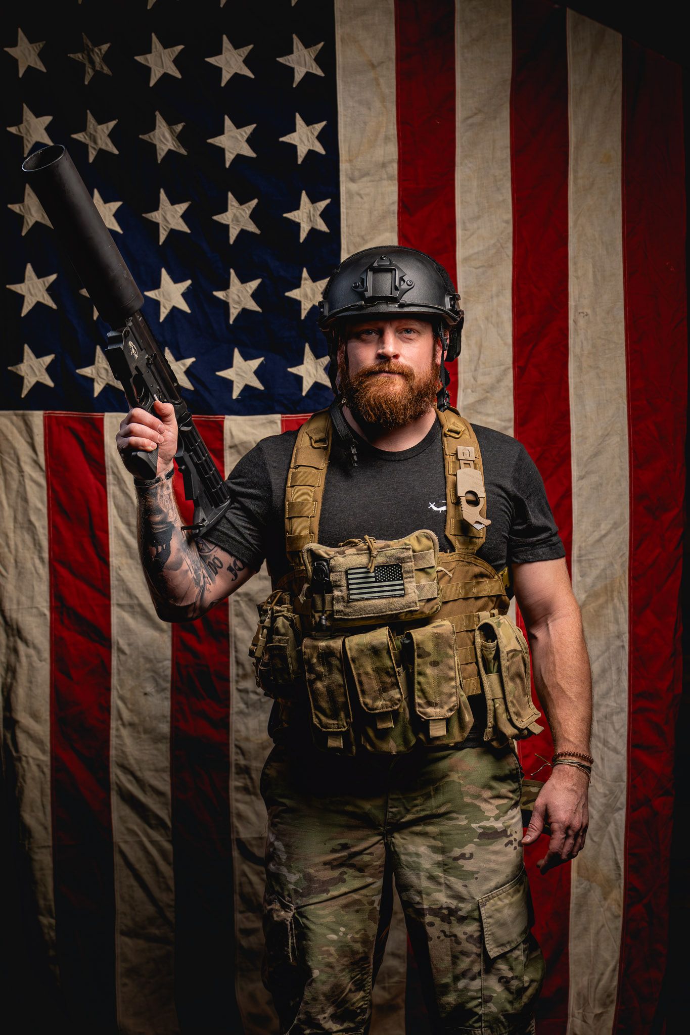 Tactical-gear-wearing veteran aiming a Can Cannon upward against a flag backdrop during a New Year creative shoot.