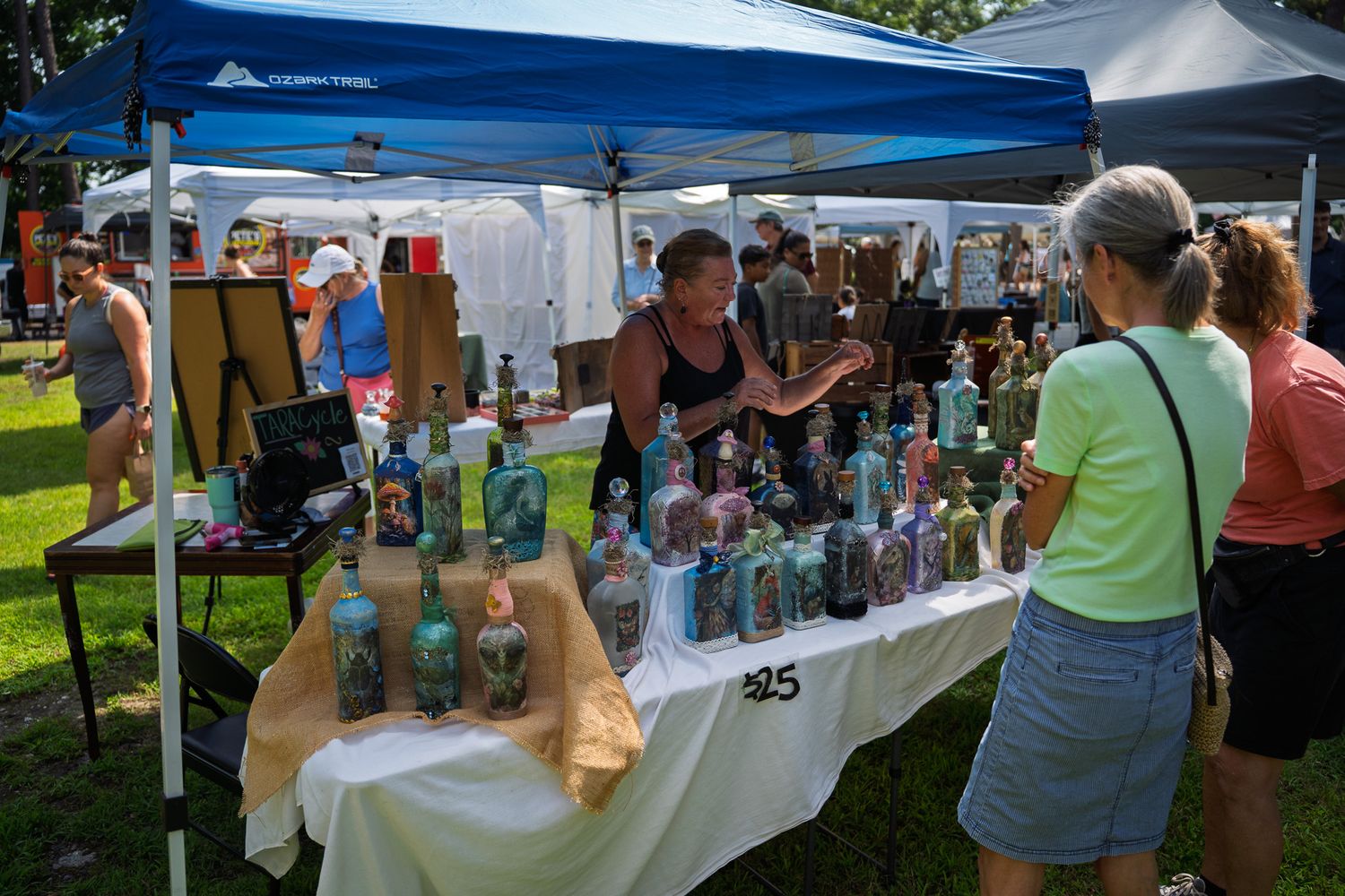 Visitors browse handcrafted decorative fairy bottles at the TaraCycle booth during Bluffton Farm and Flea in Bluffton, South Carolina.
