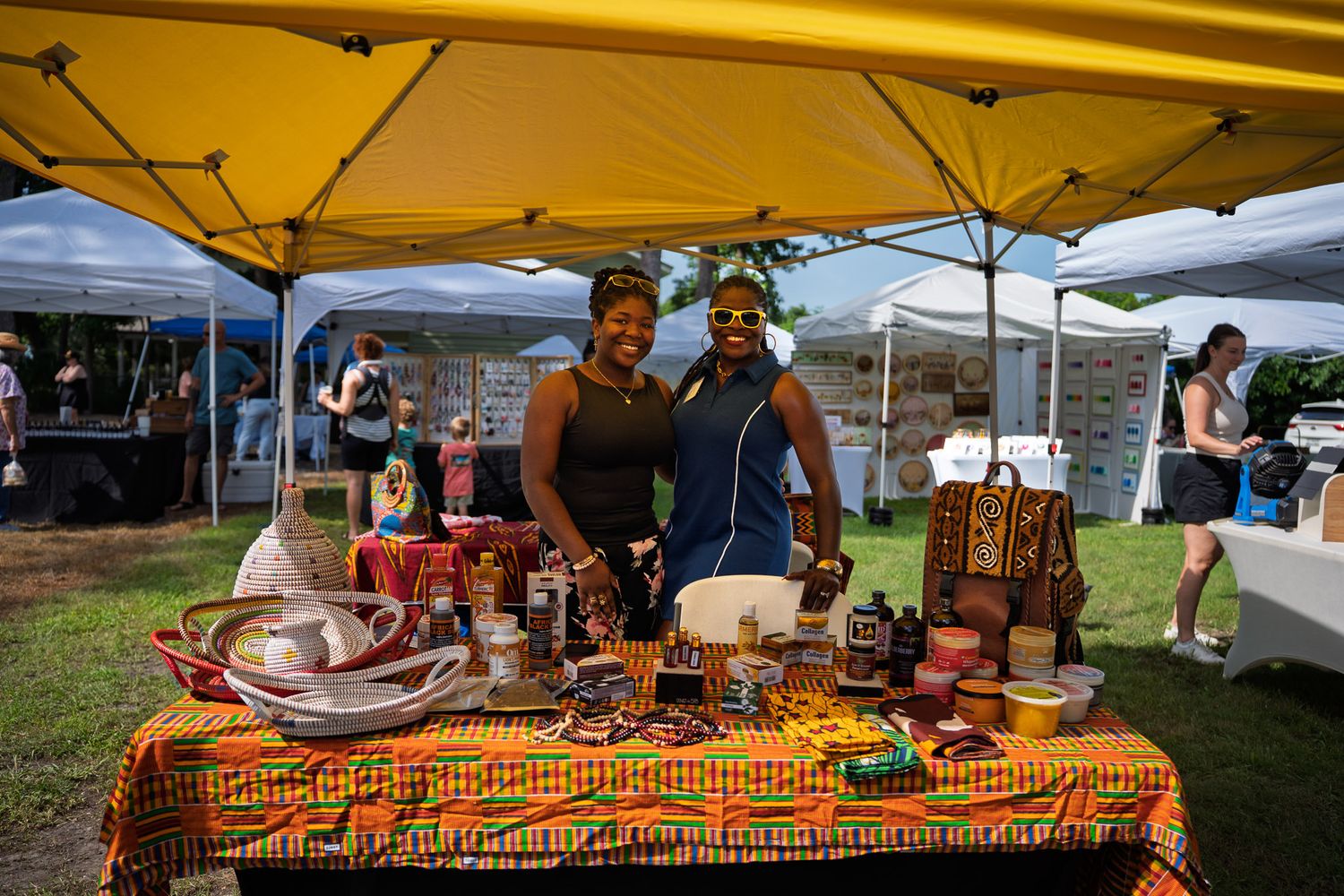 Two local vendors welcome visitors to their handcrafted goods booth during the Bluffton Farm and Flea grand opening in Bluffton, South Carol