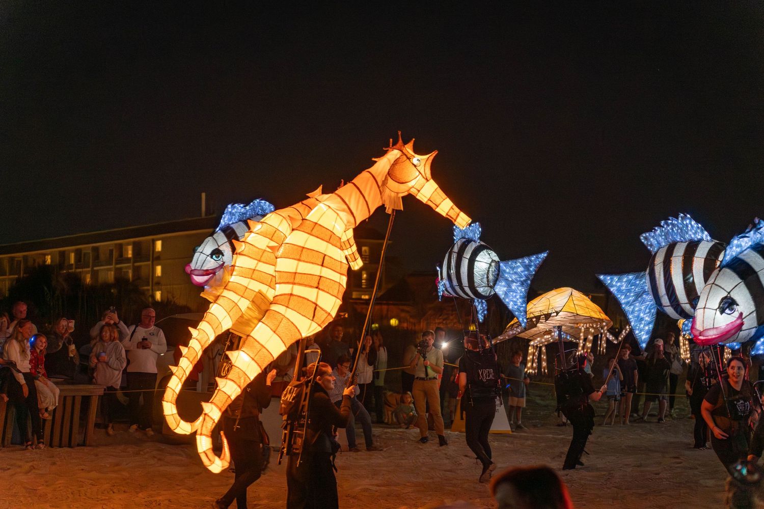 Huge illuminated seahorse and fish lanterns move along the sand at night during the Hilton Head Island Lantern Parade.