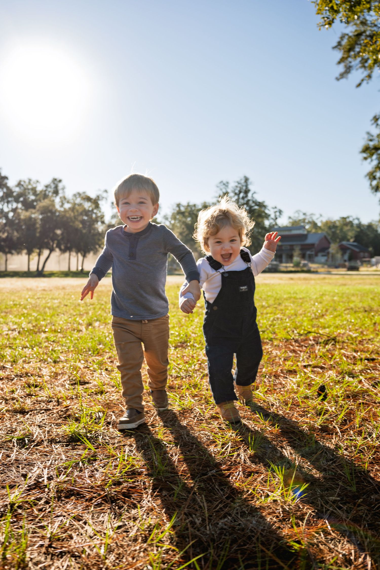 Family lifestyle photography featuring two children running outdoors during golden hour in Bluffton by GoodnRich Photography