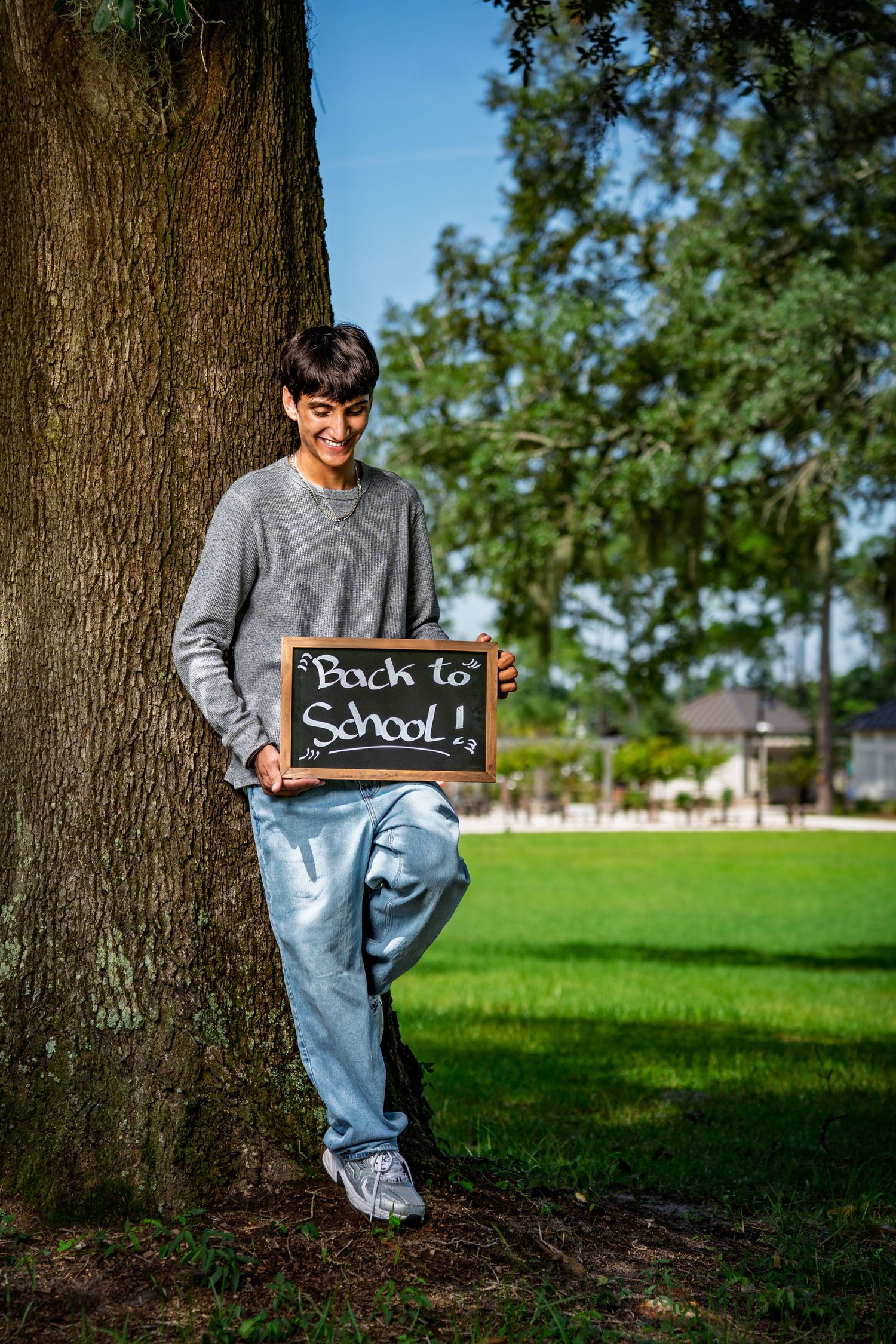 Teen student holding a Back to School sign by an oak tree at Red Barn Park at New Riverside in Bluffton, SC.