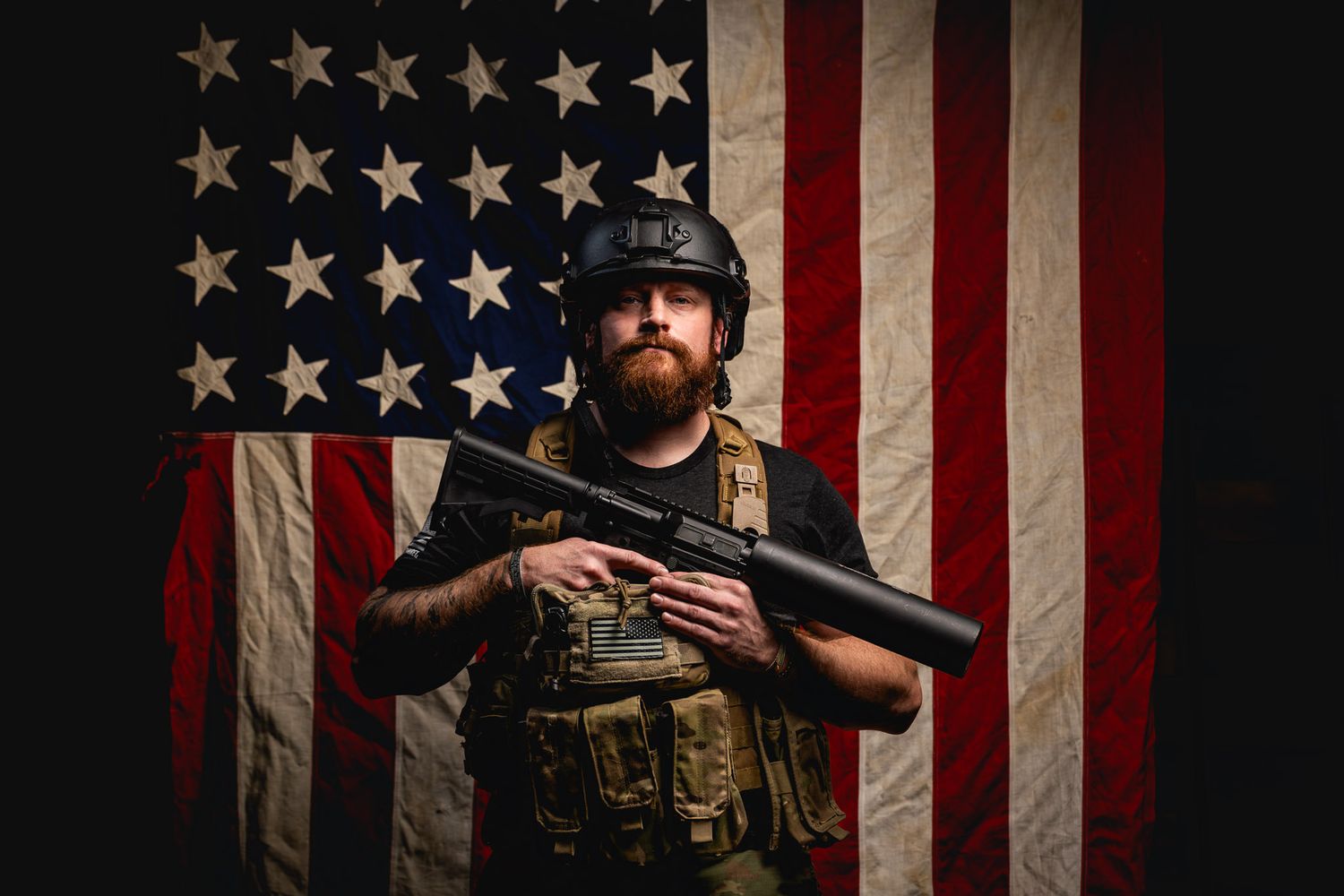 Veteran in full tactical setup confidently holding the Can Cannon in front of an American flag background.