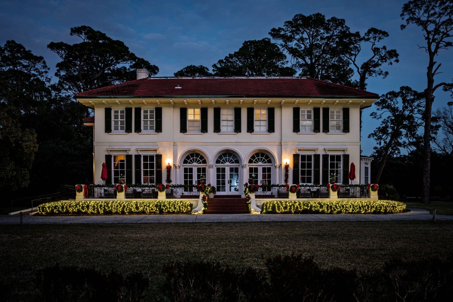 Elegant historic Jekyll Island home glowing with Christmas lights and festive décor during the holiday season at dusk.