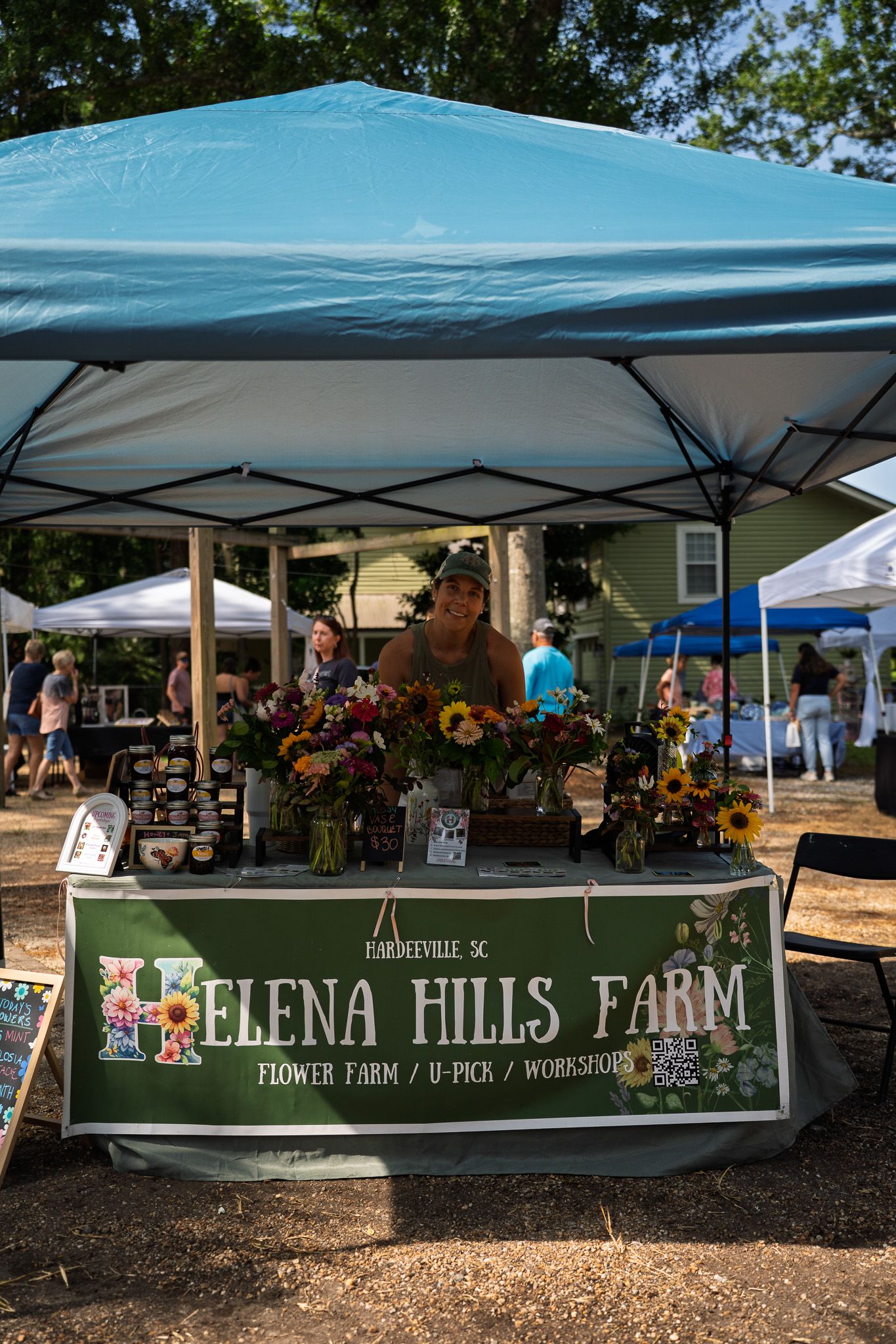 A vendor from Helena Hills Farm smiles behind colorful bouquets and locally grown flowers at Bluffton Farm and Flea.