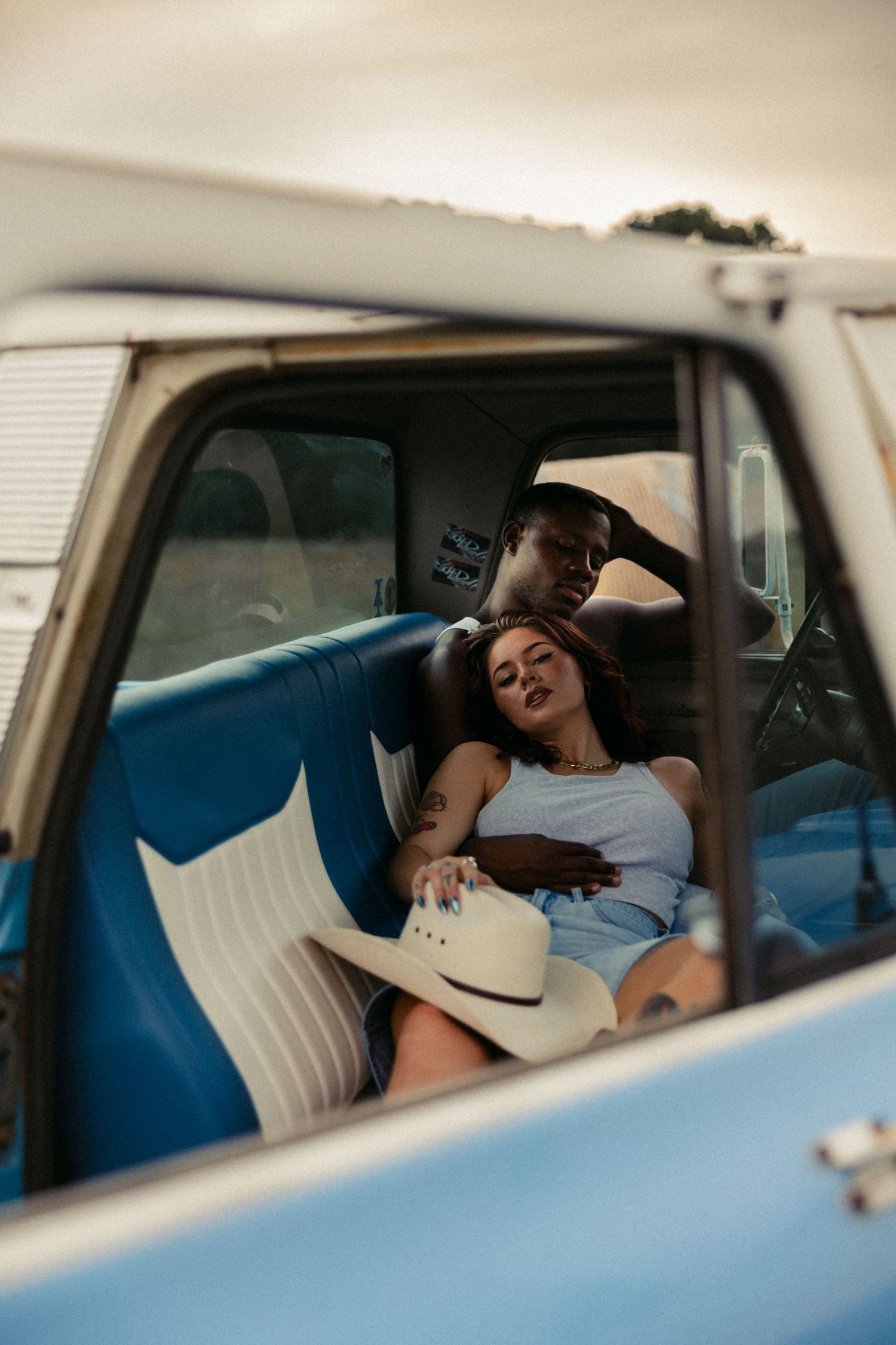 An interracial couple relaxes together on the blue bench seat of a vintage pickup truck. Tulsa Photographer
