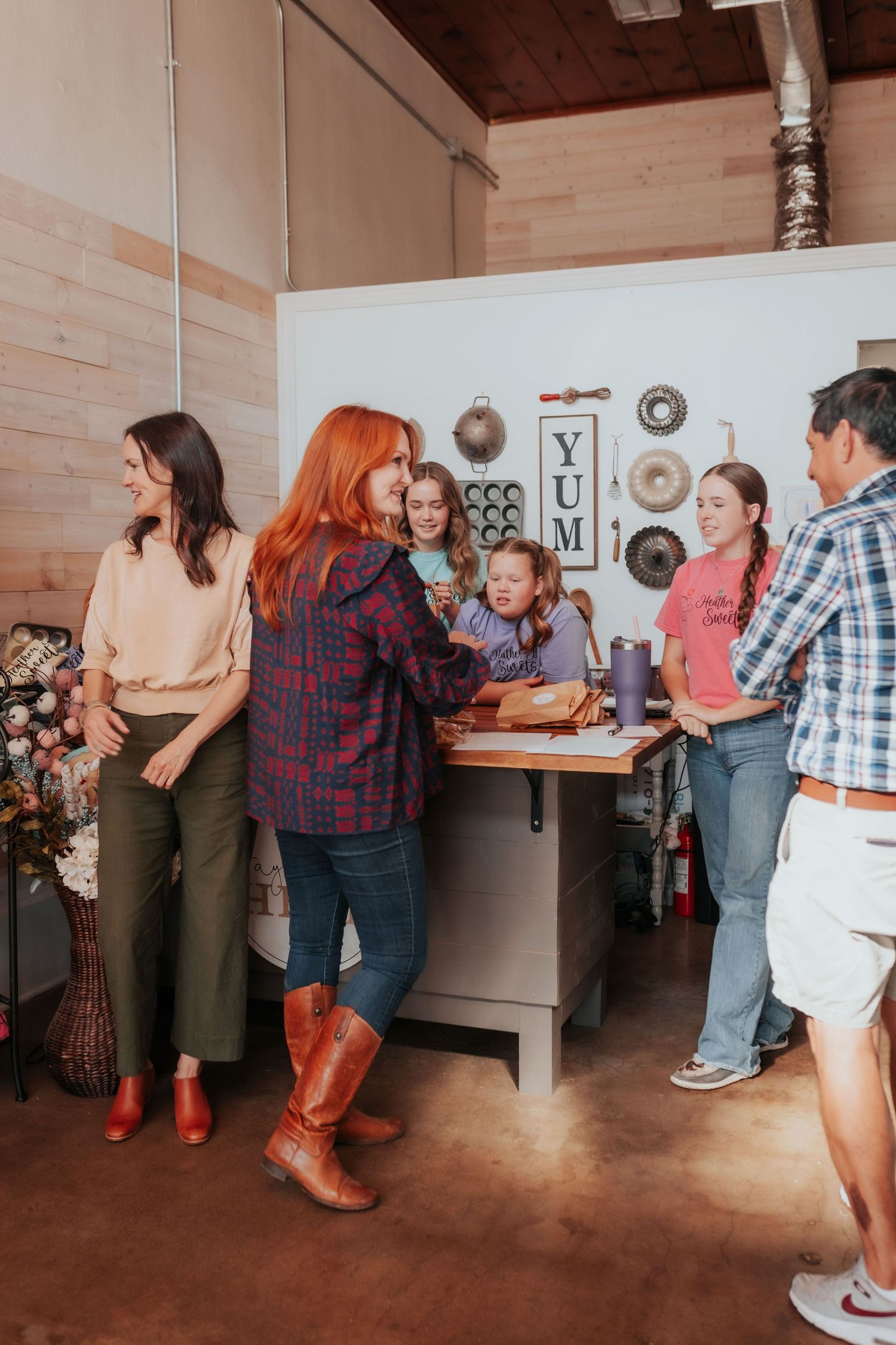 Group of people gathered around a kitchen counter in a rustic cooking studio setting. Tulsa Photographer