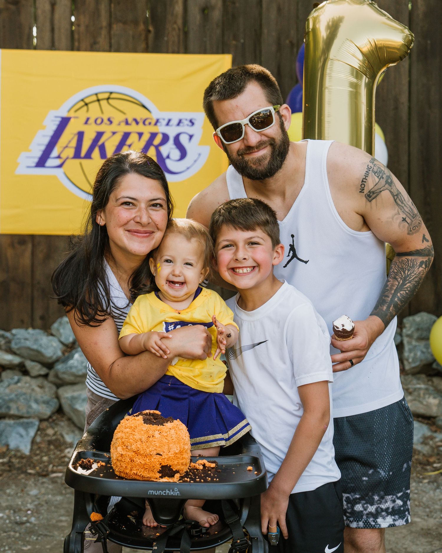 Family of four celebrating baby's first birthday with theme party, balloon and orange smash cake. Anchorage-Party-and-event-photographer