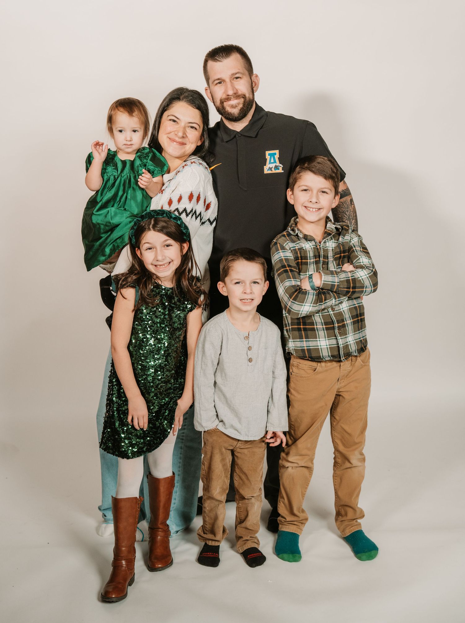 Family of six posing for a holiday portrait in a photography studio with festive holiday outfits. anchorage-family-photographer