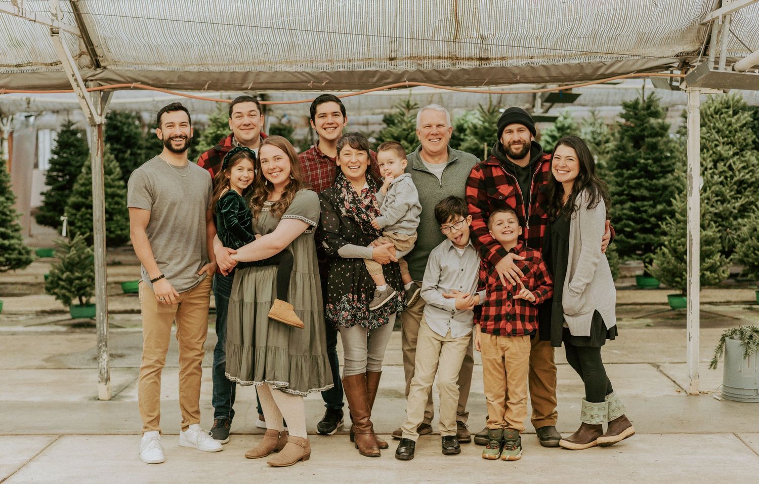 Extended family group smiling together at an outdoor Christmas tree farm during the holiday season. anchorage-family-photographer