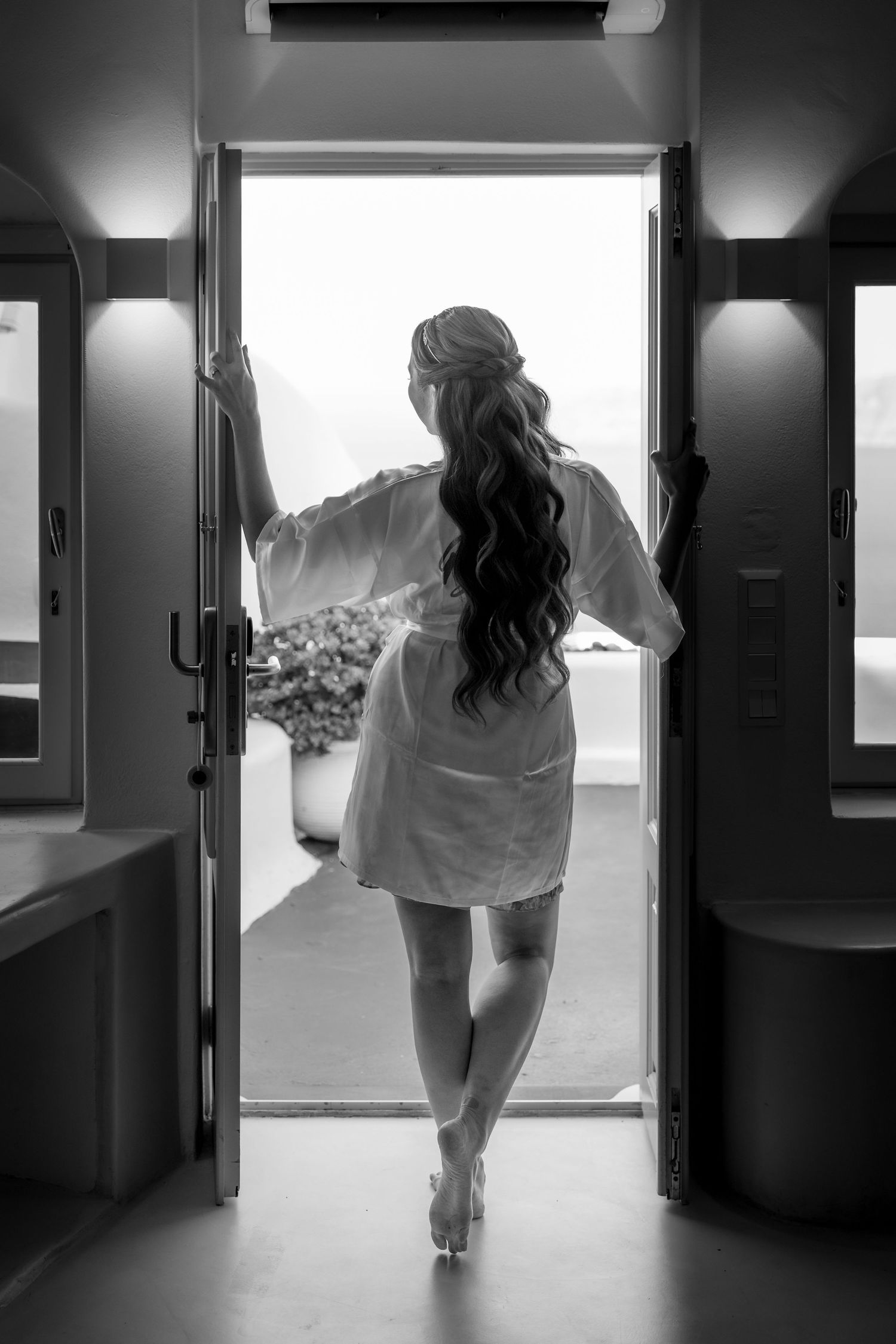 A happy bride in a wedding robe, captured at a Santorini cliffs venue during the bride's and bridesmaids' preparations in natural light