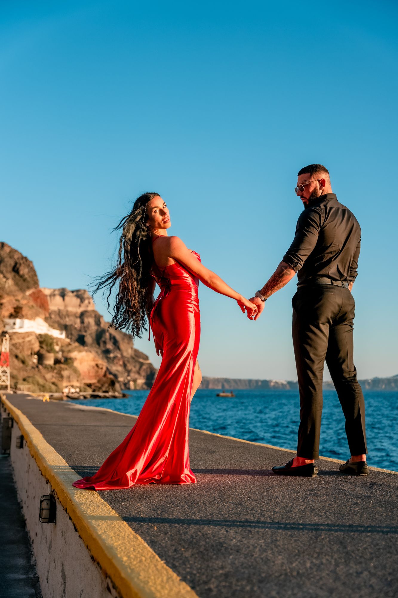 Couple walking hand in hand by the sea in a white village in Santorini, intimate and joyful