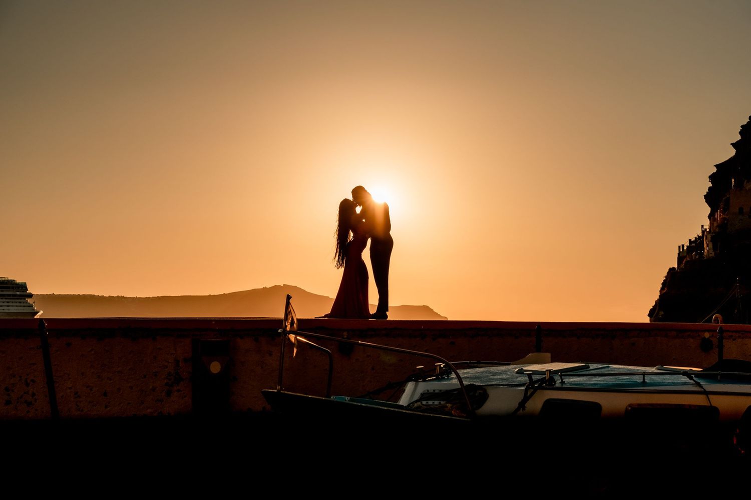 Groom proposing to bride by the sea on a Santorini dock at sunset, capturing love and excitement 🌅