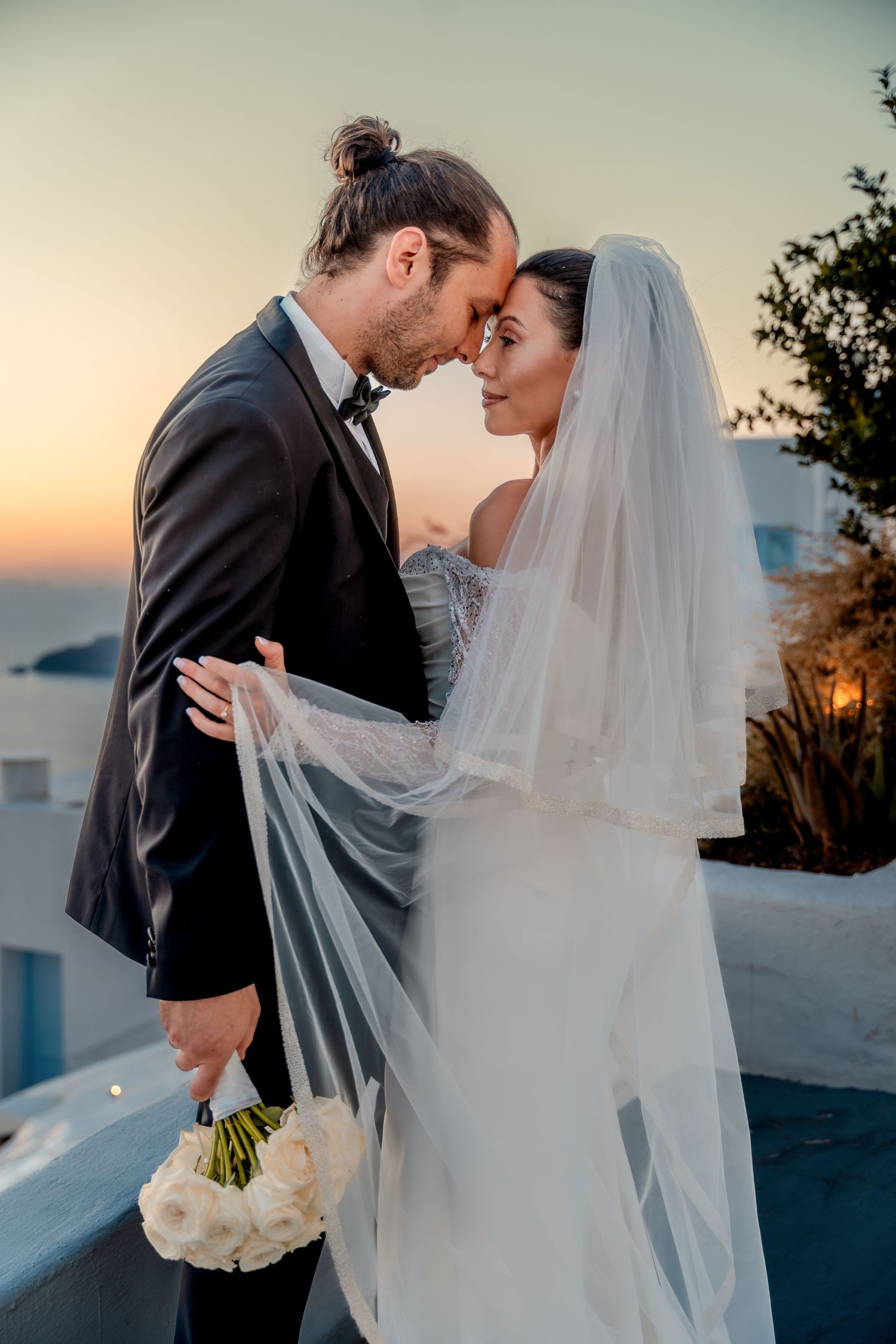 Bride and groom holding hands in Santorini at sunset 🌅