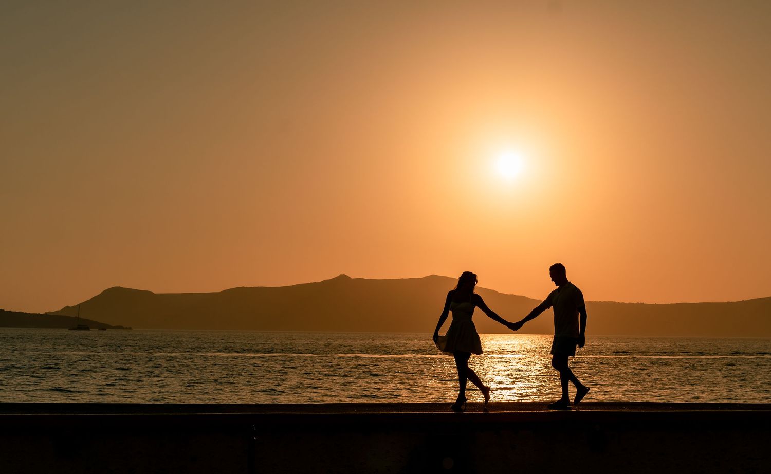 Couple walking hand in hand in sunset after their Elopement. Romantic moment captured on a Santorini bay, celebrating love and togetherness