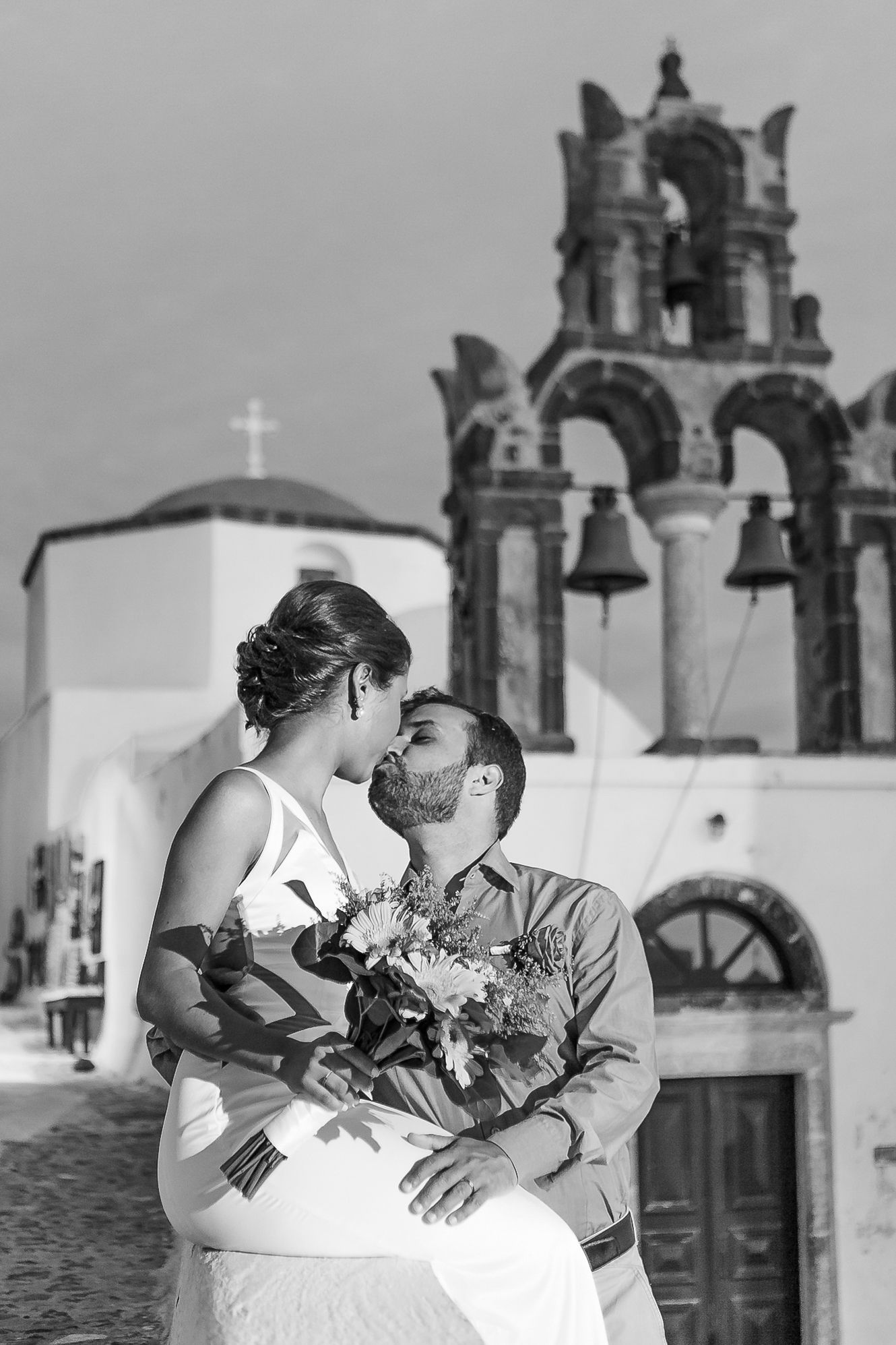 Newlyweds embracing in Santorini, natural light highlighting joy and intimacy