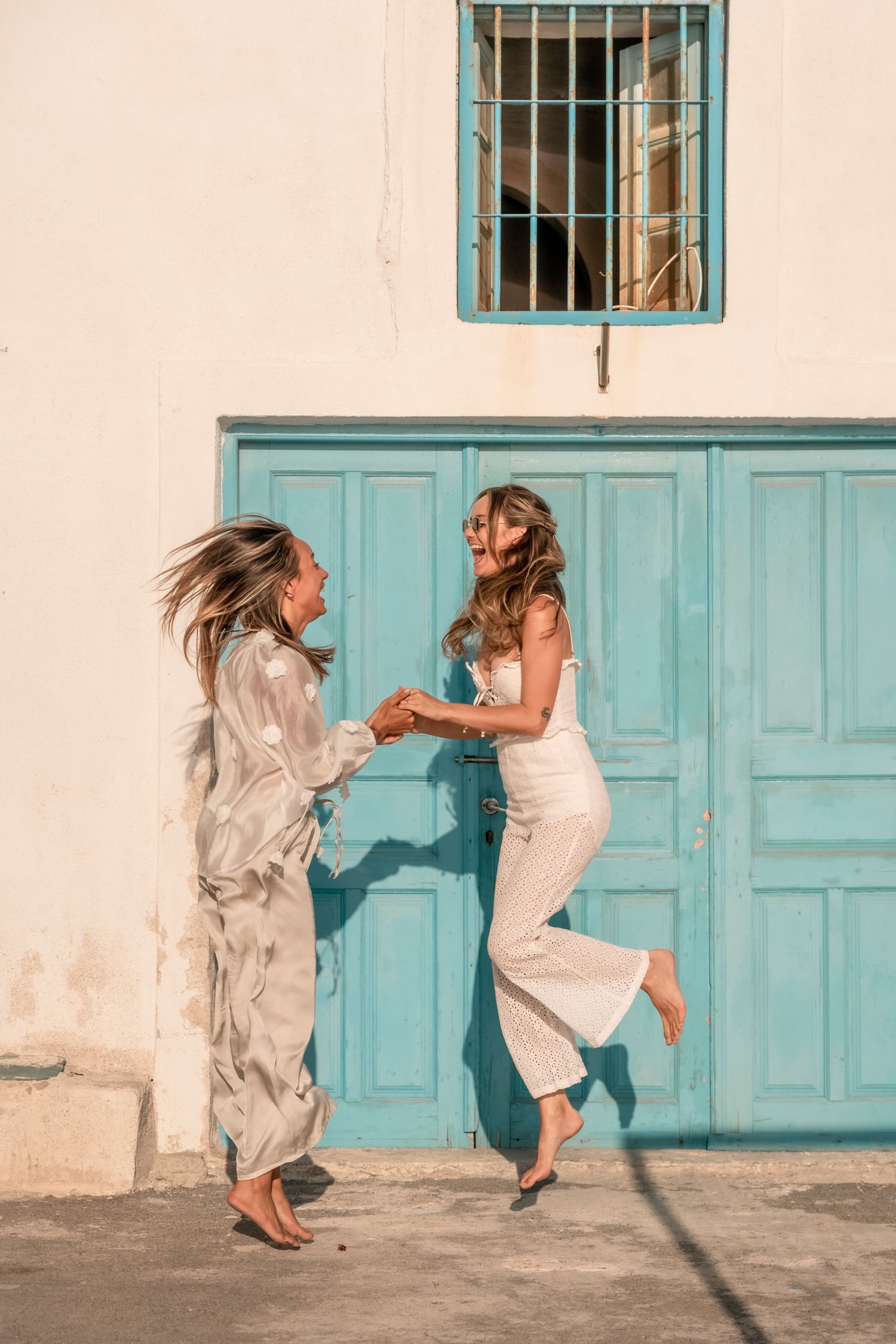 Friends sharing laughter during a lifestyle shoot in Santorini in white and blue, joyful and light-filled
