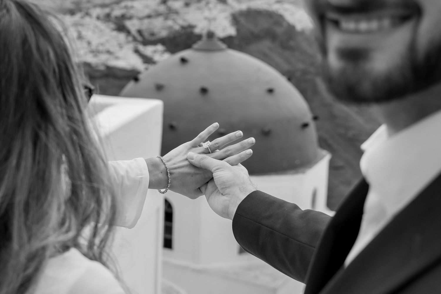 Bride says yes during an intimate proposal on the cliffs of Santorini. The couple embraces timeless moments on a terrace with love and joy
