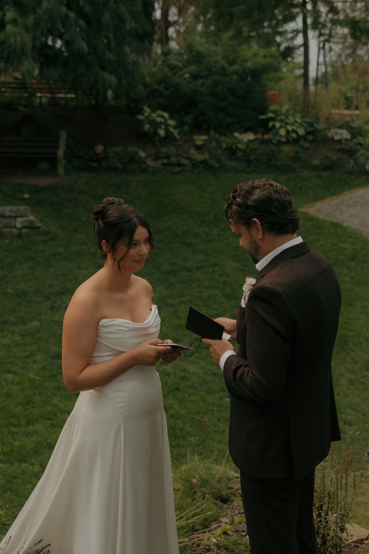 Bride and groom exchanging handwritten vows during an intimate outdoor garden wedding ceremony.