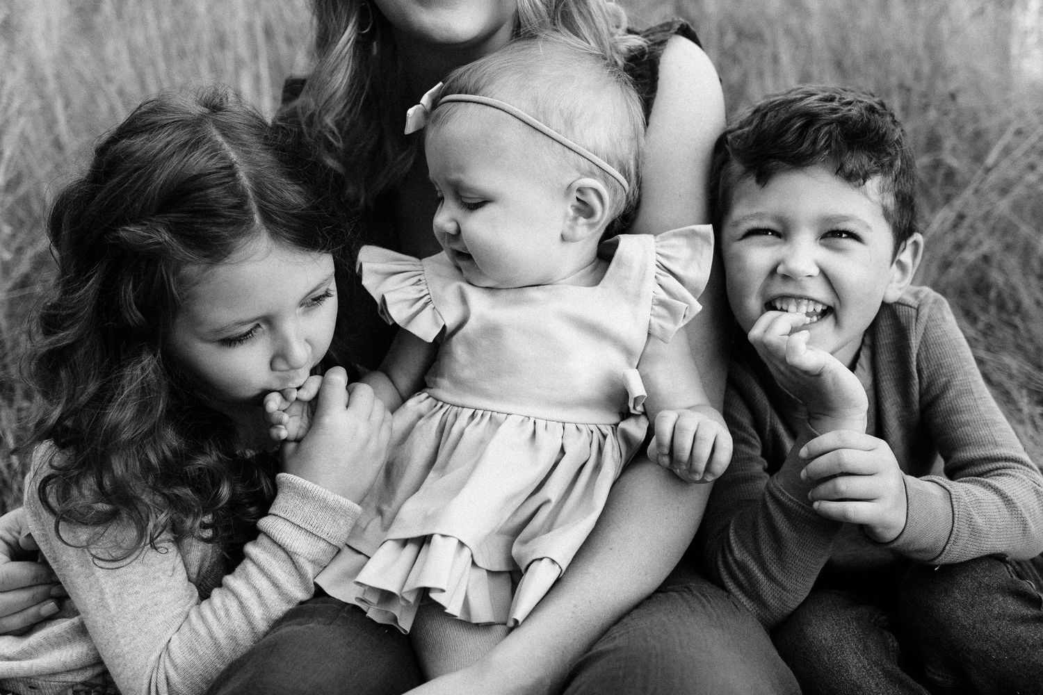 Three happy little kids snuggled in their mom's lap.