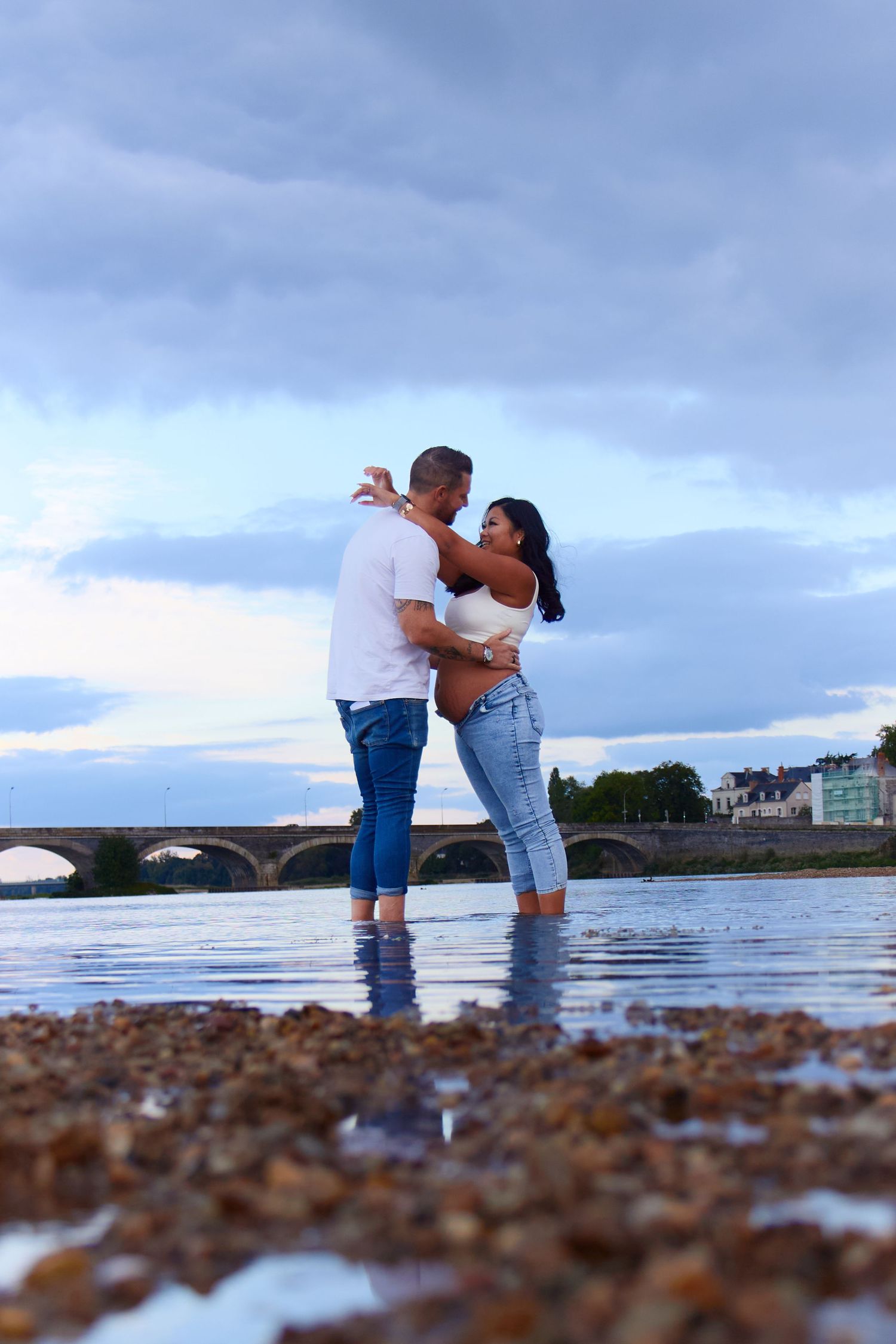 Couple standing in shallow water sharing romantic moments at sunset.