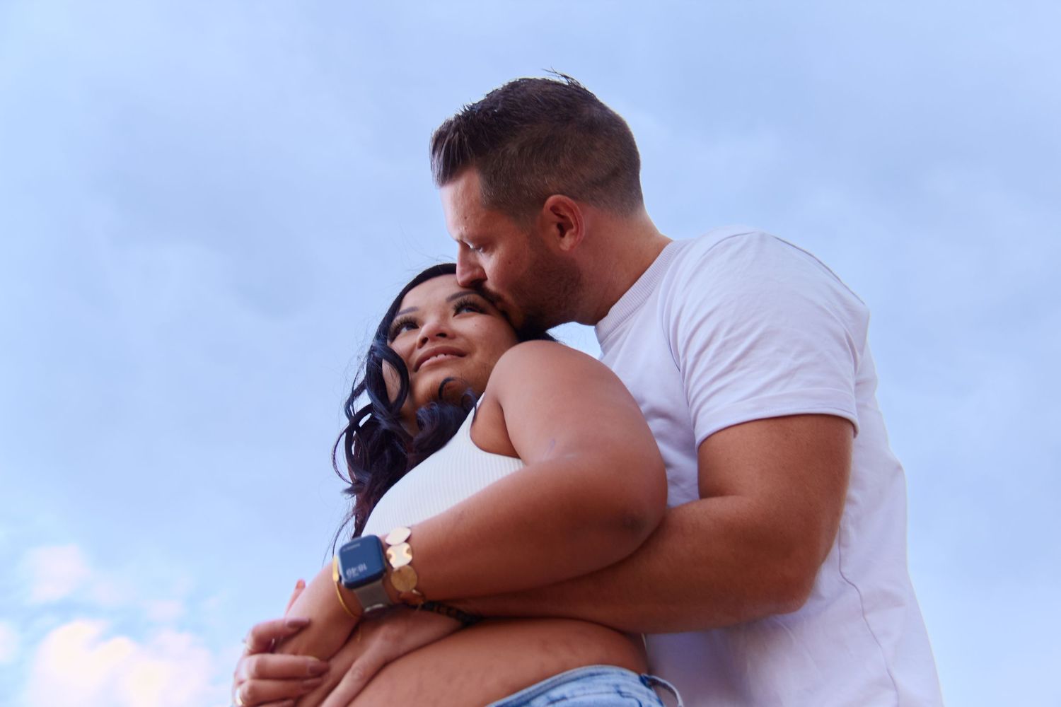 Couple embracing against blue sky background.