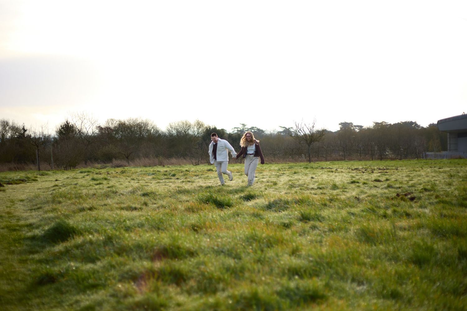 Couple walking together through a green spring meadow during golden hour.