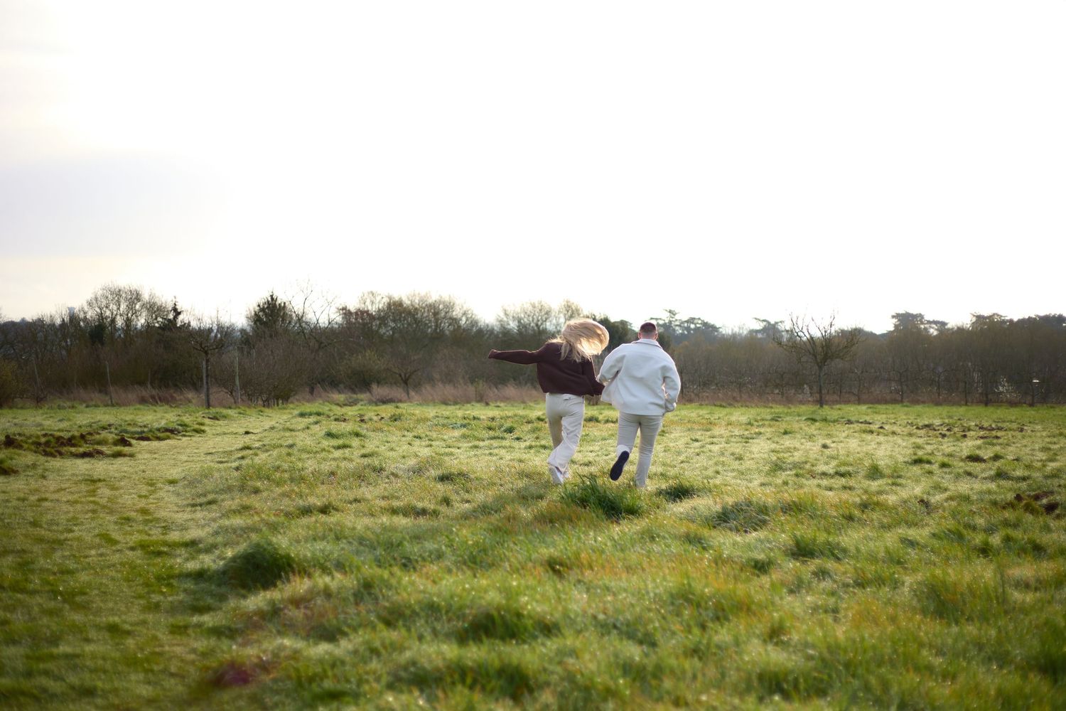 Couple walking together through a scenic green meadow on a bright spring day.