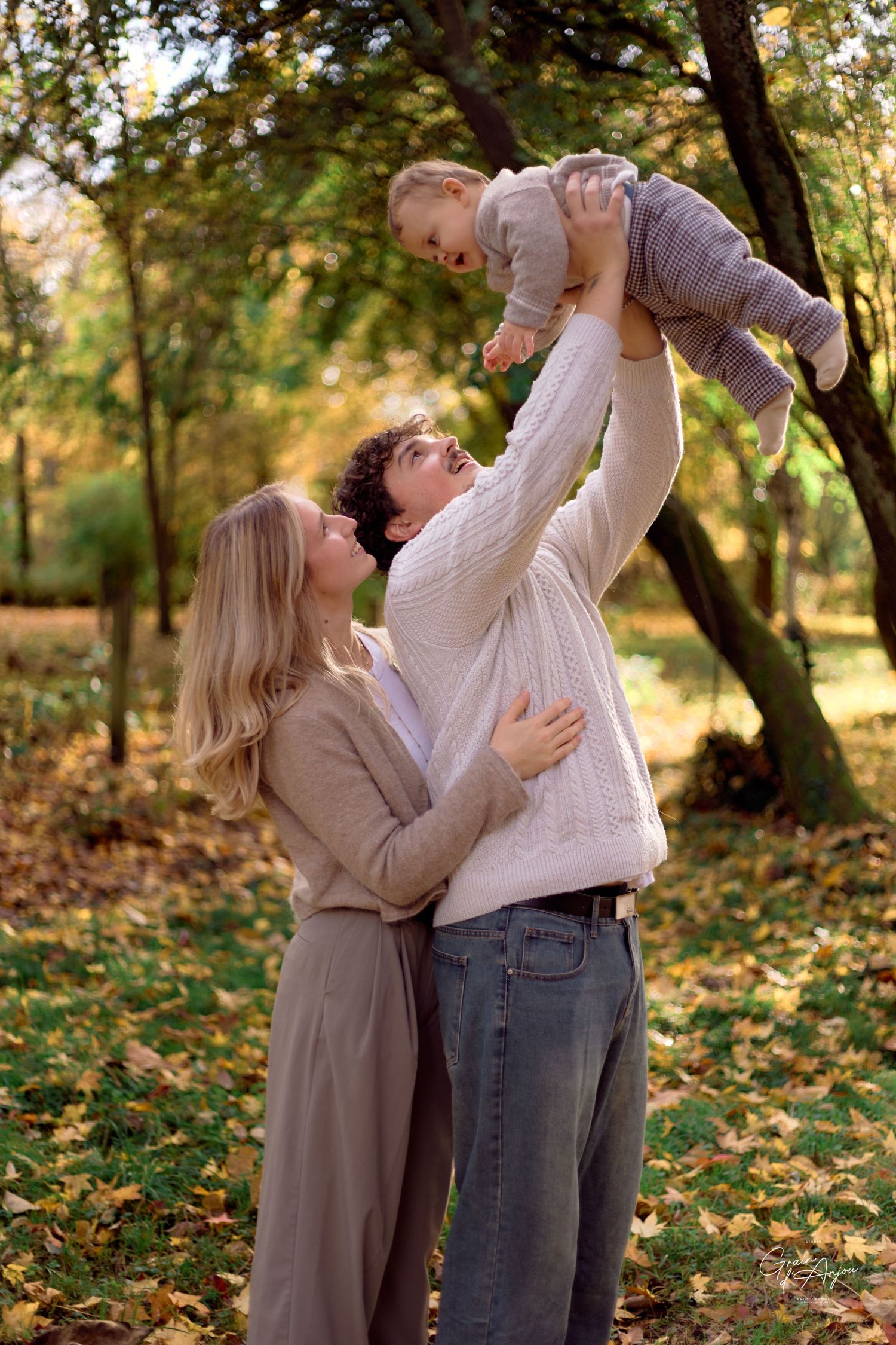 A couple plays and laughs together in a park filled with autumn leaves.