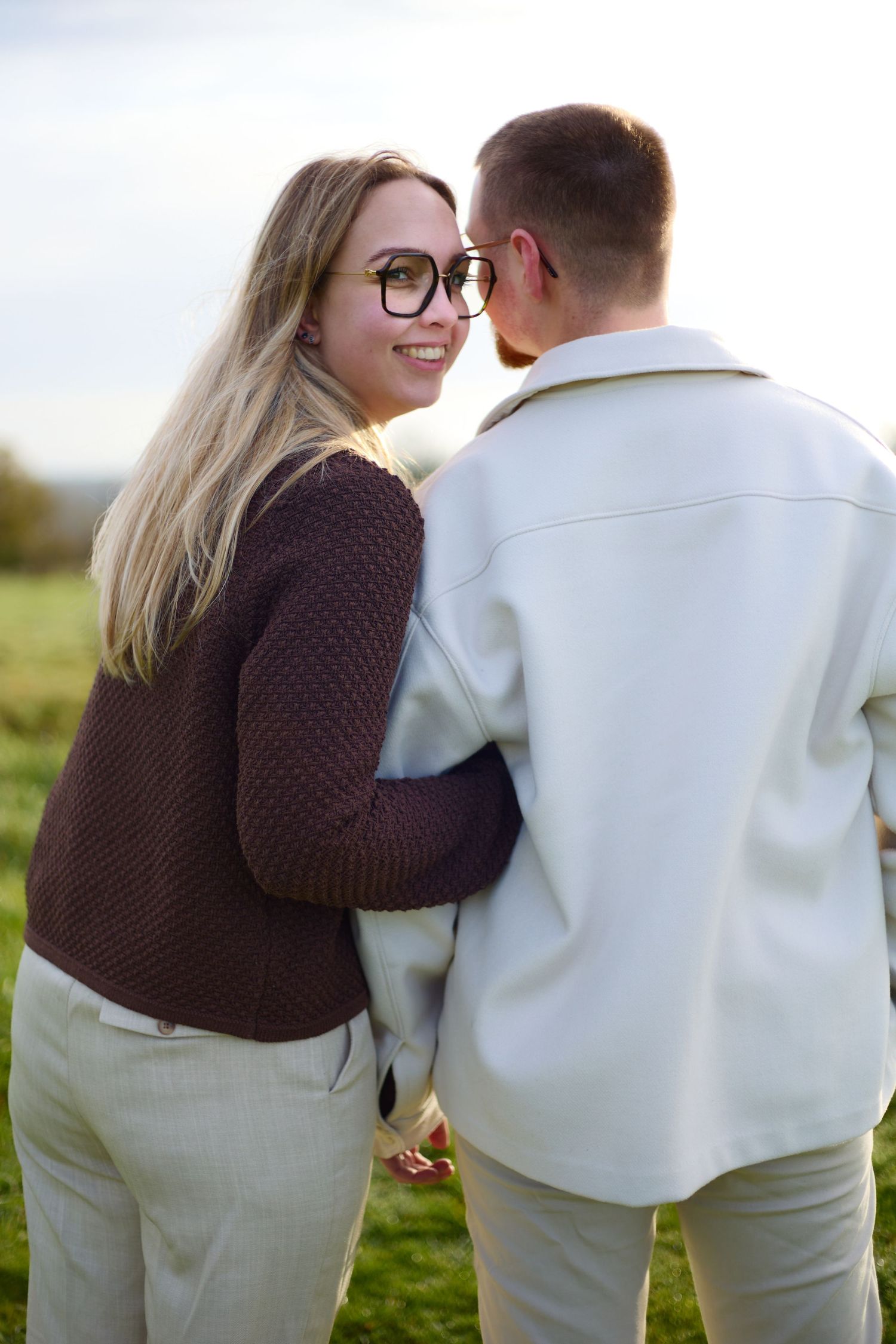 Romantic couple moment captured in coordinated cream and brown outfits.
