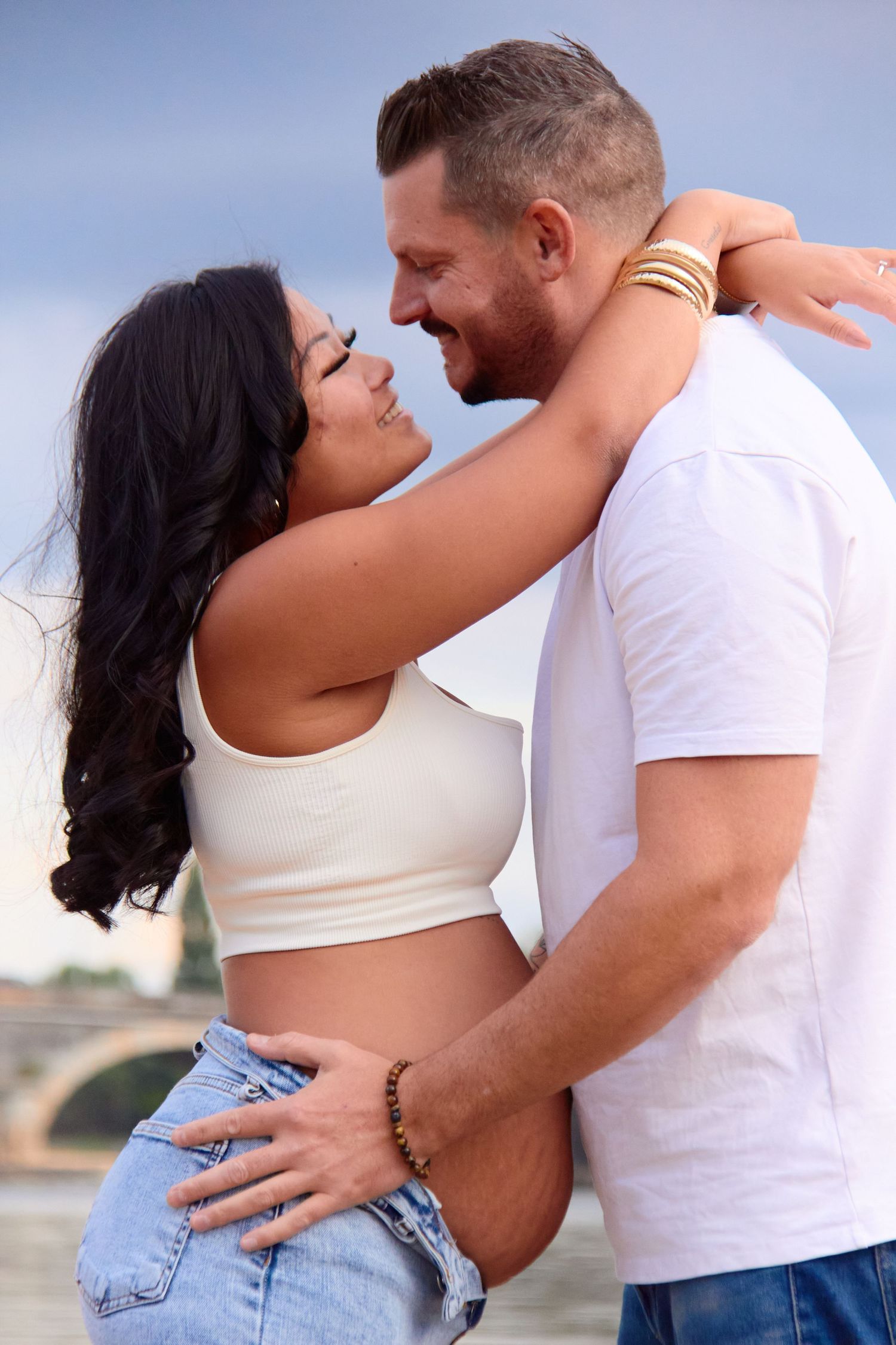A couple in casual white tops and jeans share intimate moments during an outdoor photoshoot.